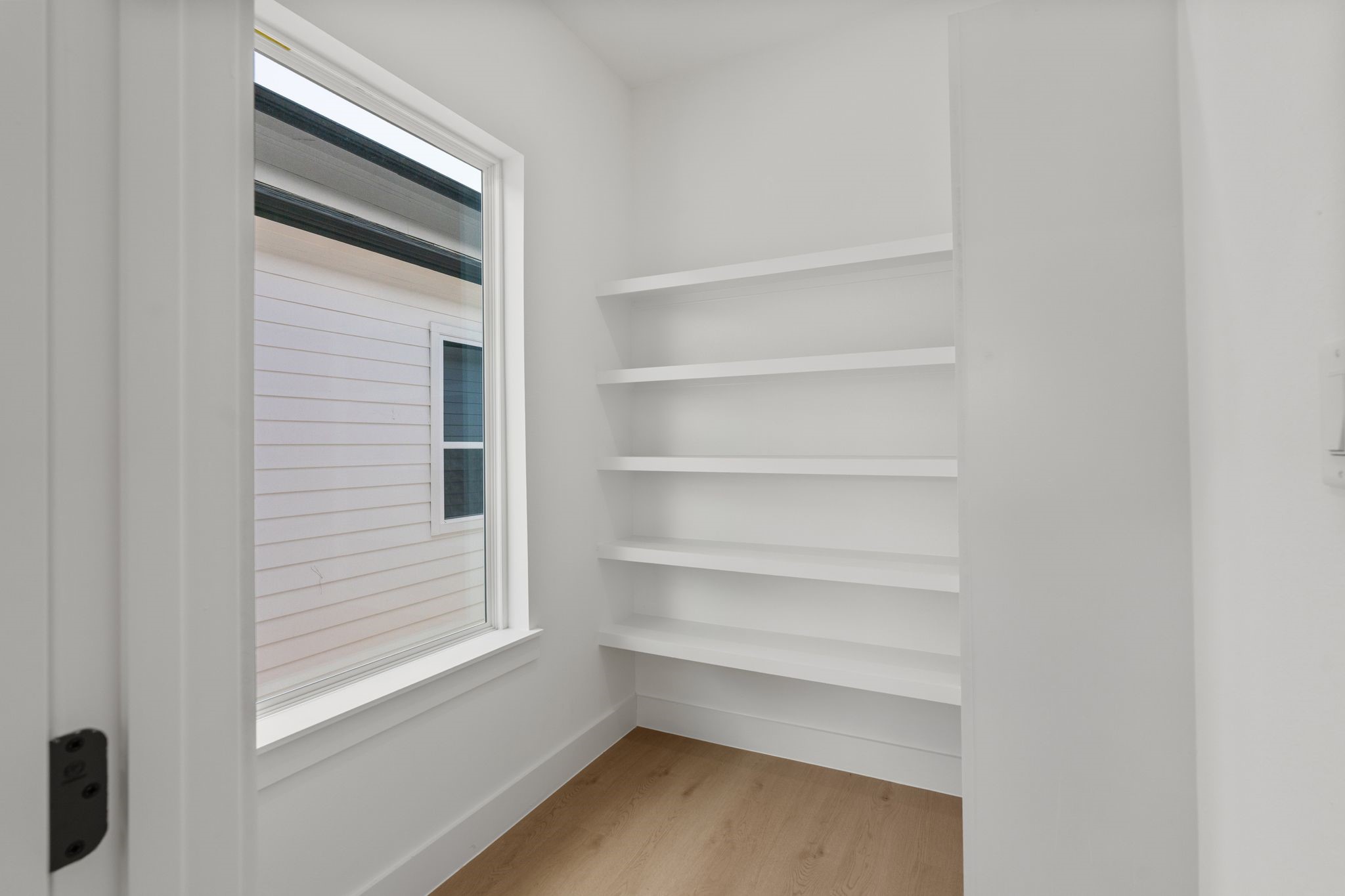 Bright and airy storage space featuring built-in shelves and a large window for natural light.