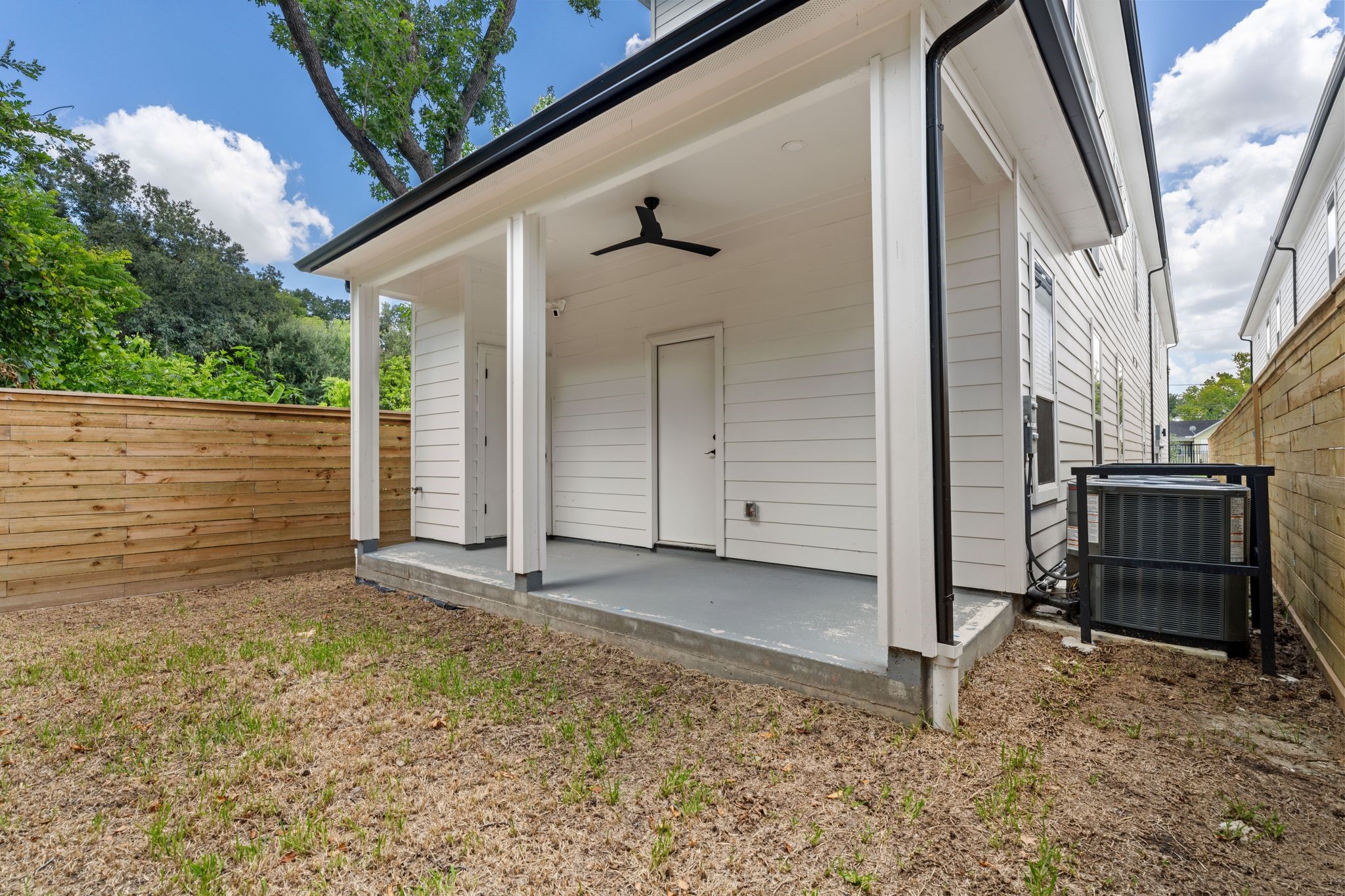 Charming covered patio with a ceiling fan overlooks a private, fenced backyard, perfect for relaxation or entertaining.