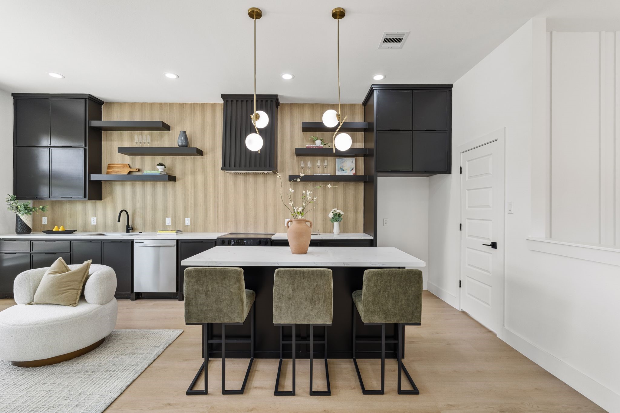 Sleek modern kitchen featuring a large island with stylish pendant lighting, open shelving, and elegant black cabinetry for a chic and functional space.