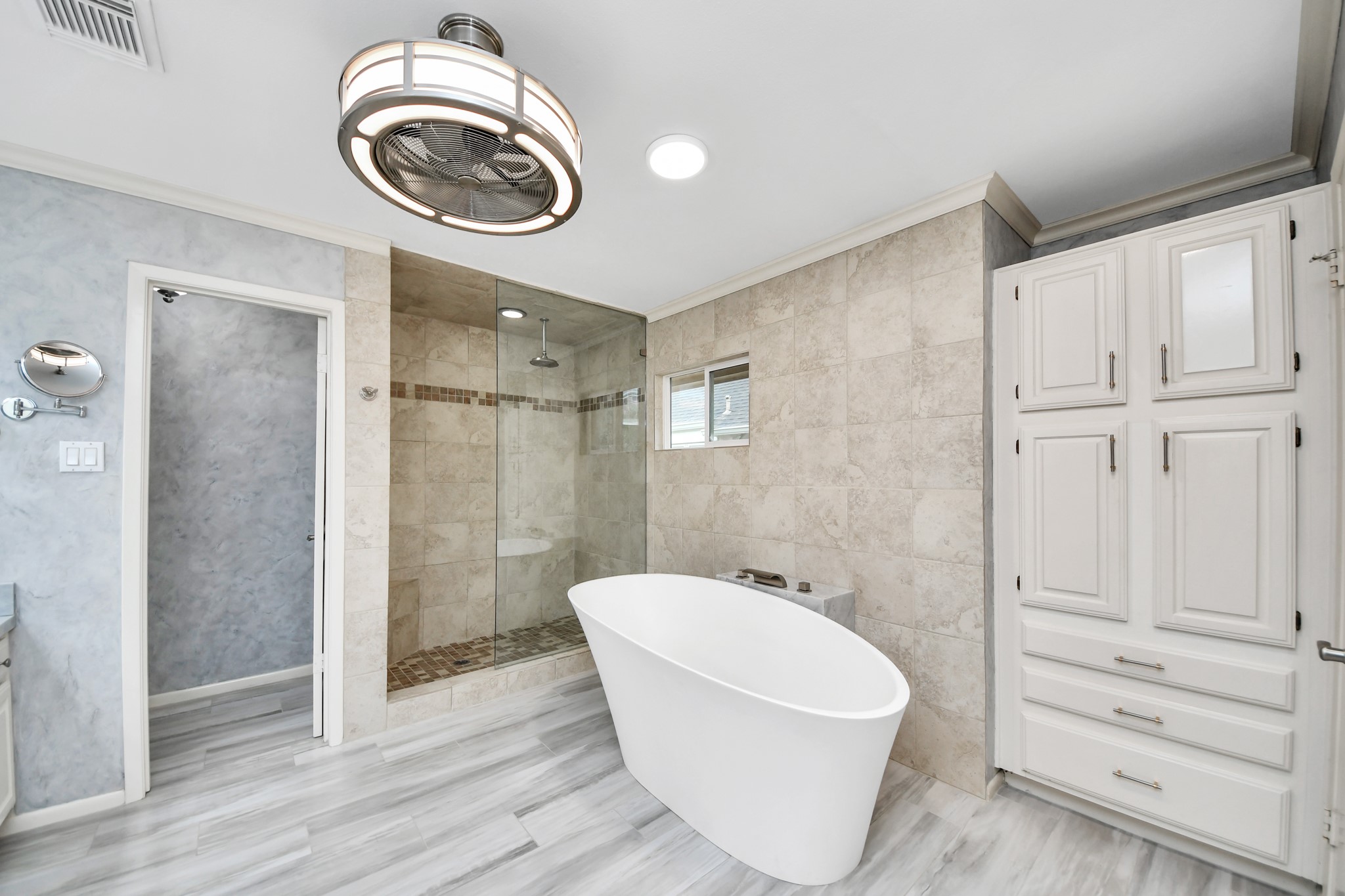 Beautifully remodeled primary bath features a freestanding Jacuzzi brand soaking tub, oversized walk-in shower and extensive built-in storage.