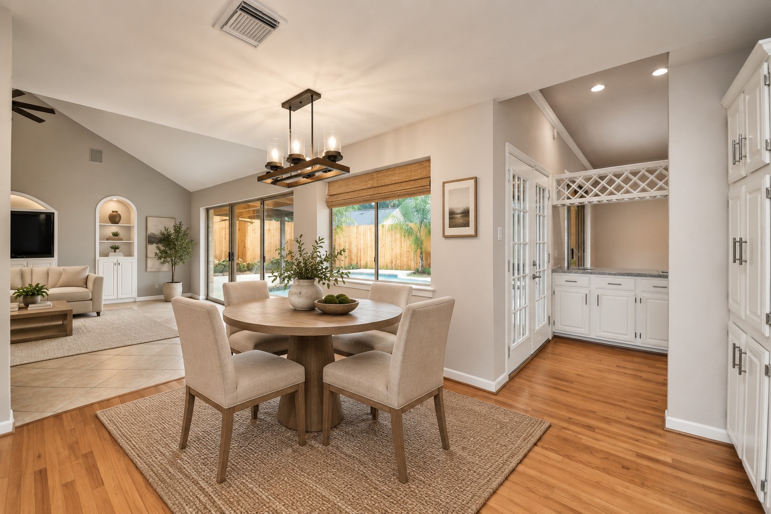 Virtually staged breakfast room shows how comfortably the space accommodates a breakfast table while maintaining an open flow to the family room. Vaulted family room, with oversized windows and sliding glass doors draw your eye toward the pool.