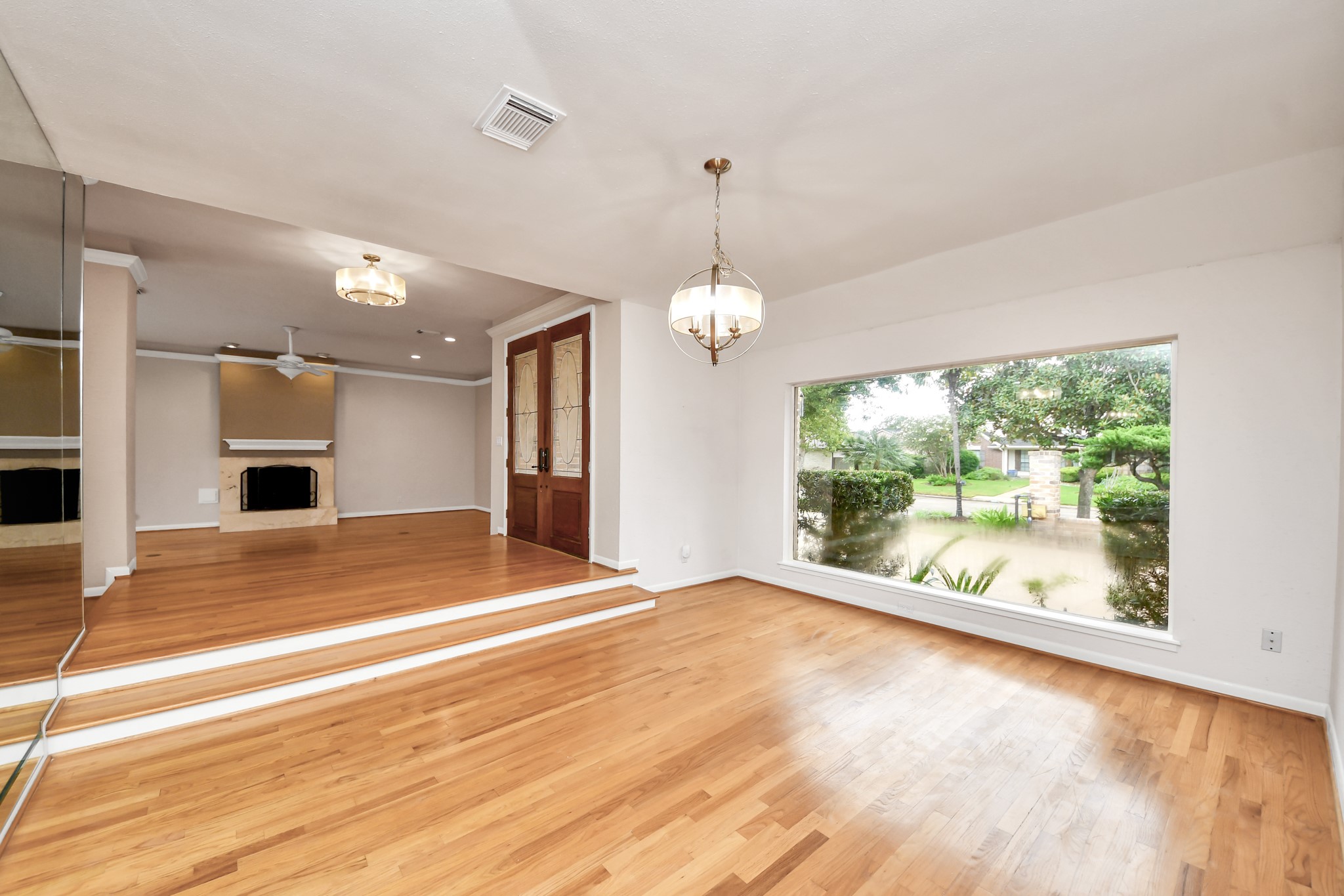 The oversized seamless picture window is a standout feature, bringing natural light and front garden views into the dining room. Wood floors and designer lighting complete the space.