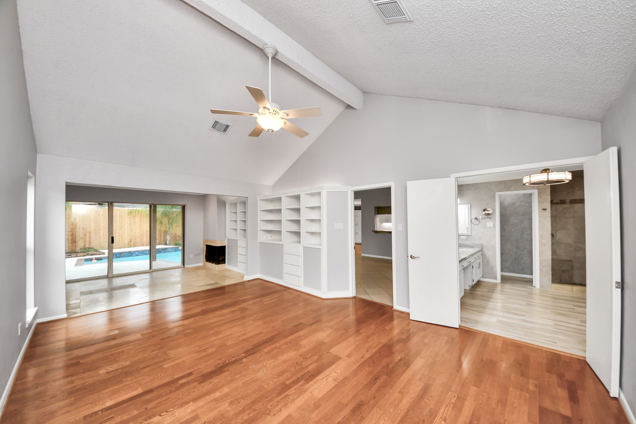 Unstaged view highlights the vaulted ceiling, wood floors and generous proportions of the primary bedroom, with direct access to the adjoining flex space and bath.
