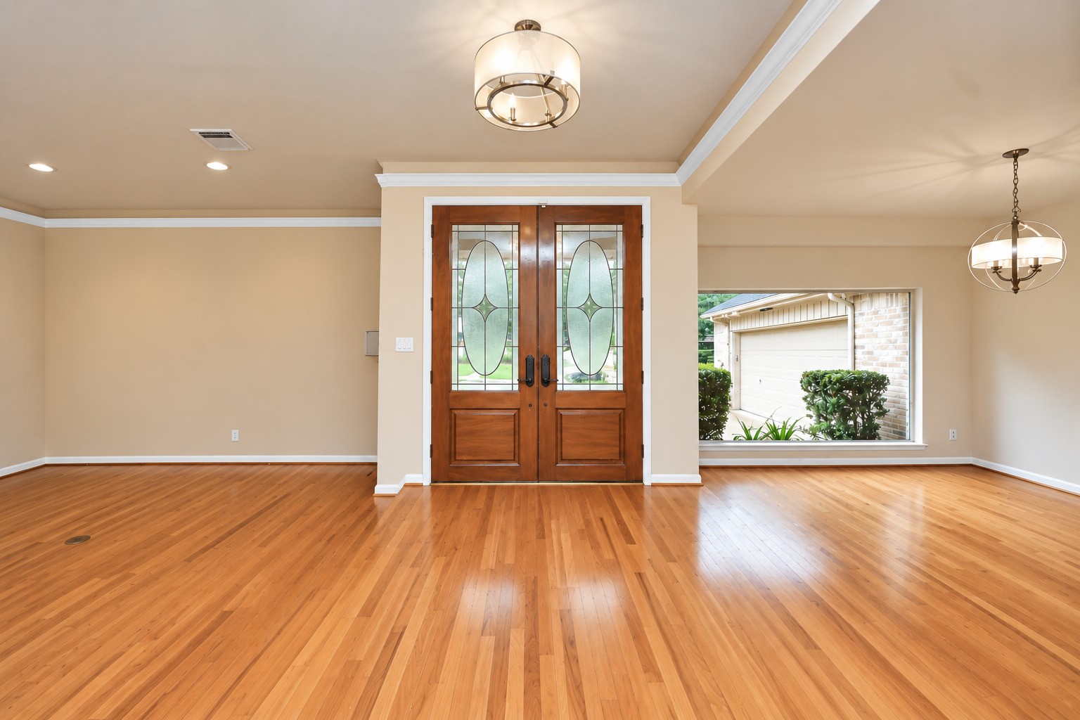 Double-door entry opens to an airy, light-filled floor plan with wood floors extending through the entry, dining room and main living area. Designer lighting and oversized windows add to the open feel.