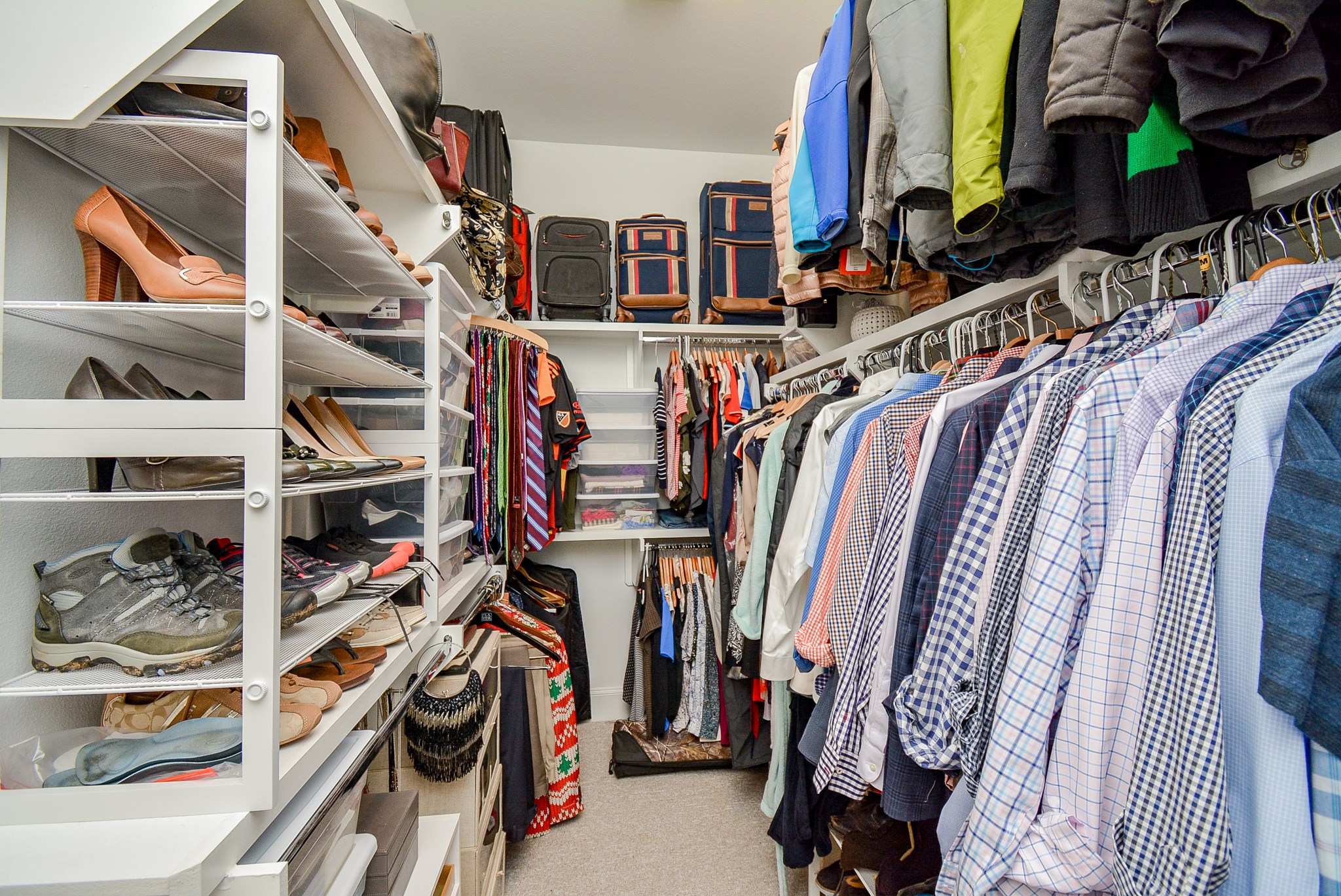 Primary bedroom walk in closet with built in shelving