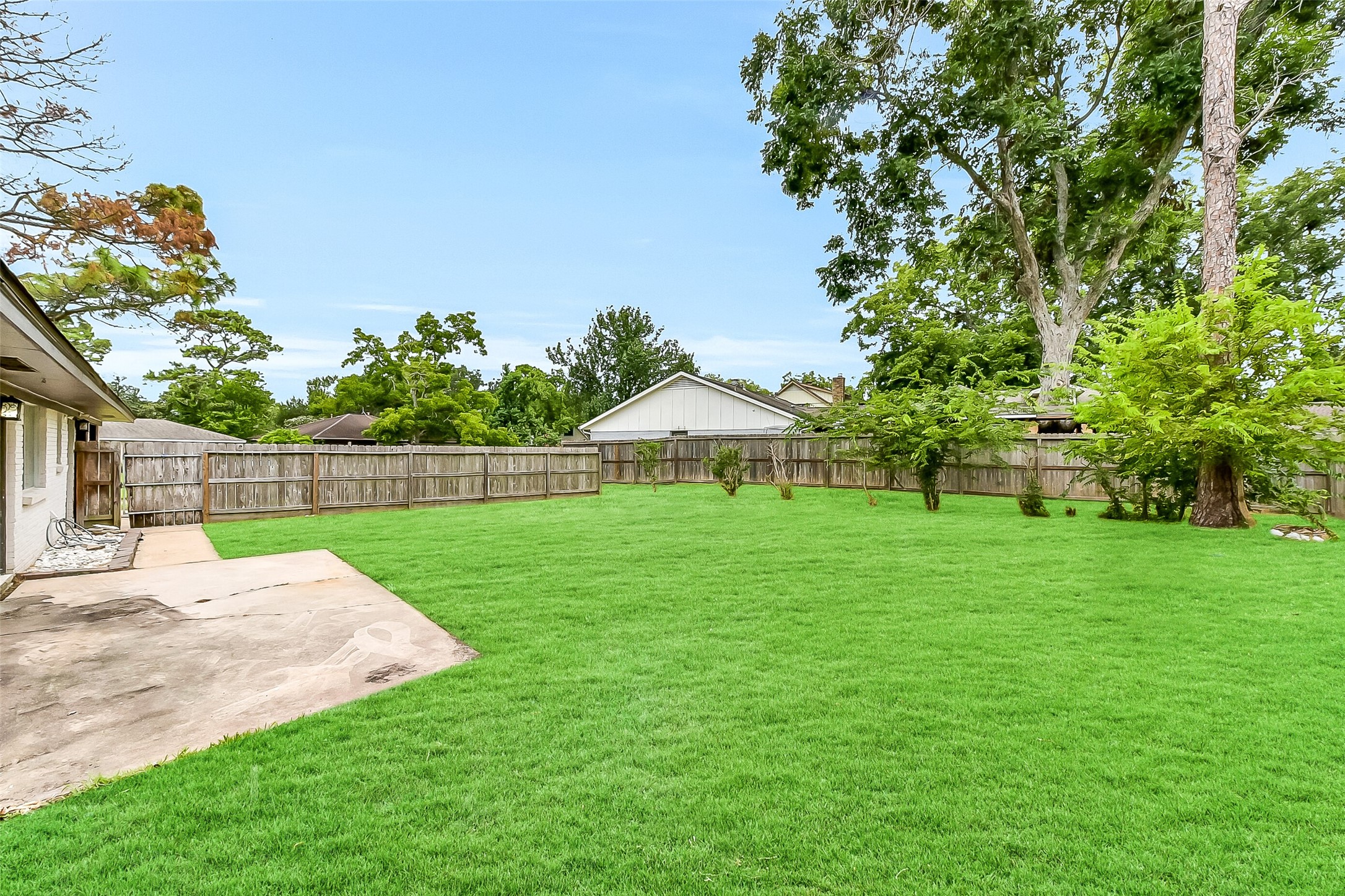 Expansive fenced backyard with a concrete patio area, mature trees, and plenty of open green spaceperfect for outdoor living, gardening, or entertaining. Also includes a whole-house Generac generator for peace of mind.