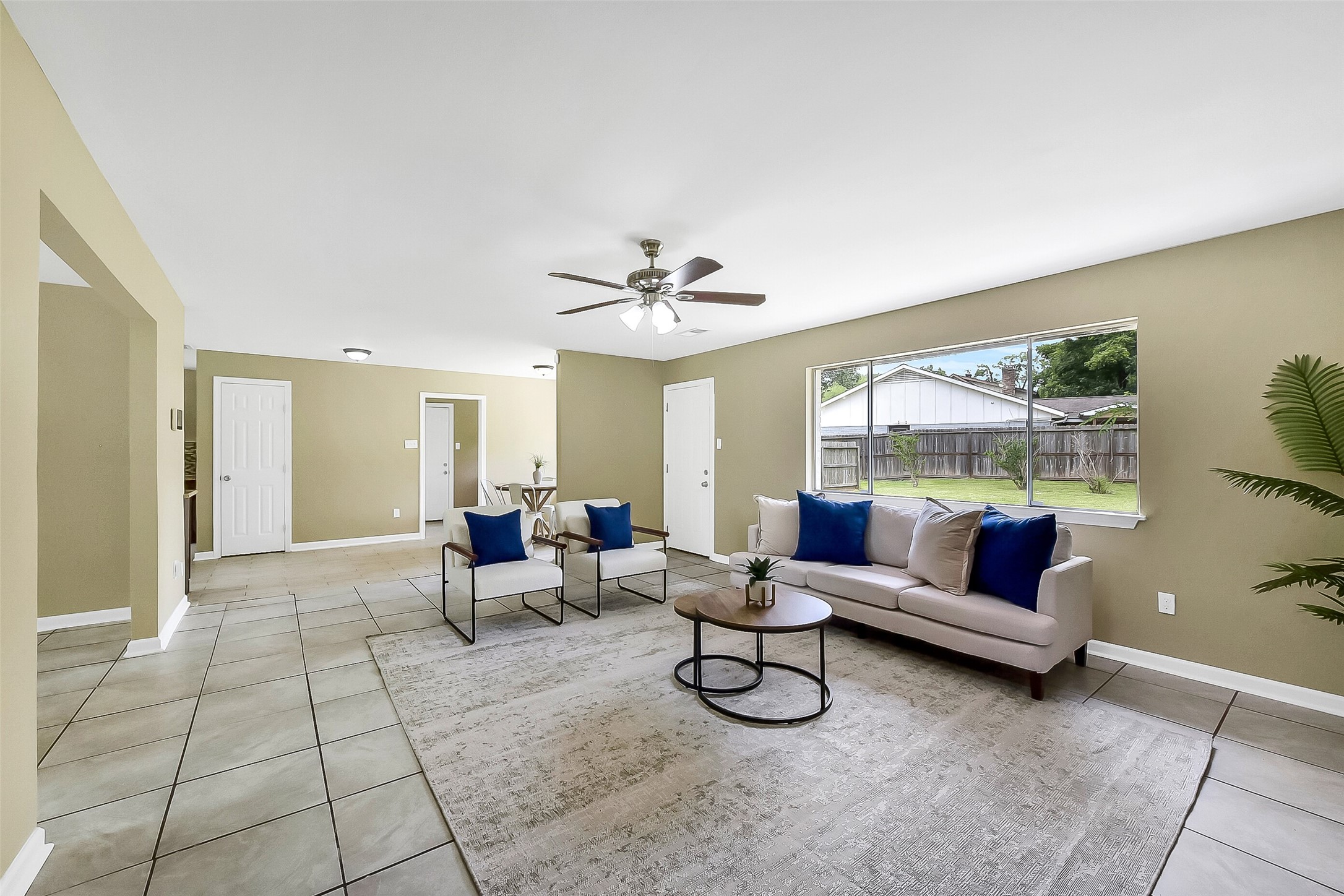 Continue into this spacious family room with a cozy brick fireplace, large windows for natural light, neutral tones, and easy-care tile flooring that flows into the dining area.
