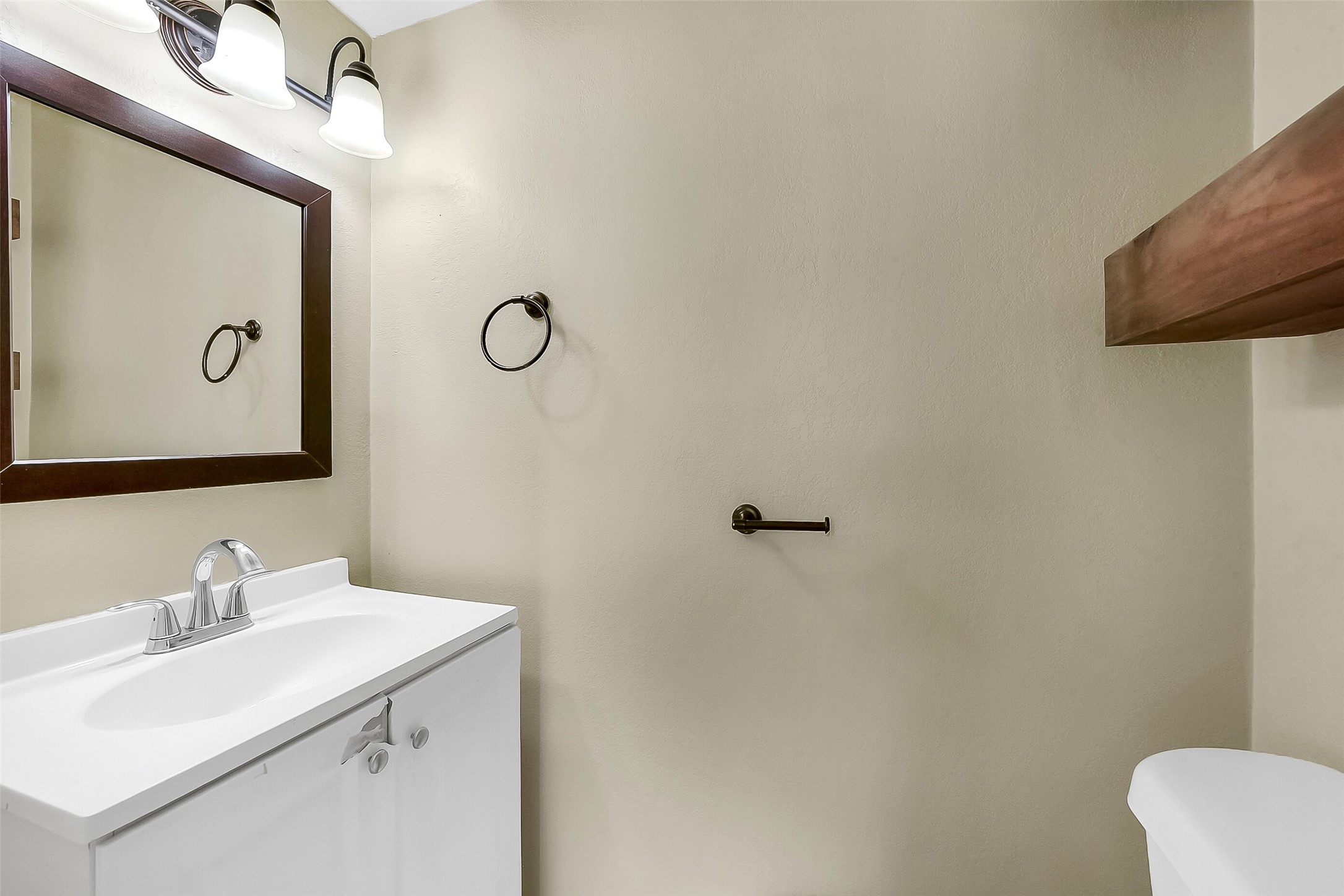 Convenient first-floor half bath with updated vanity, framed mirror, and modern light fixture, offering both style and function for guests.