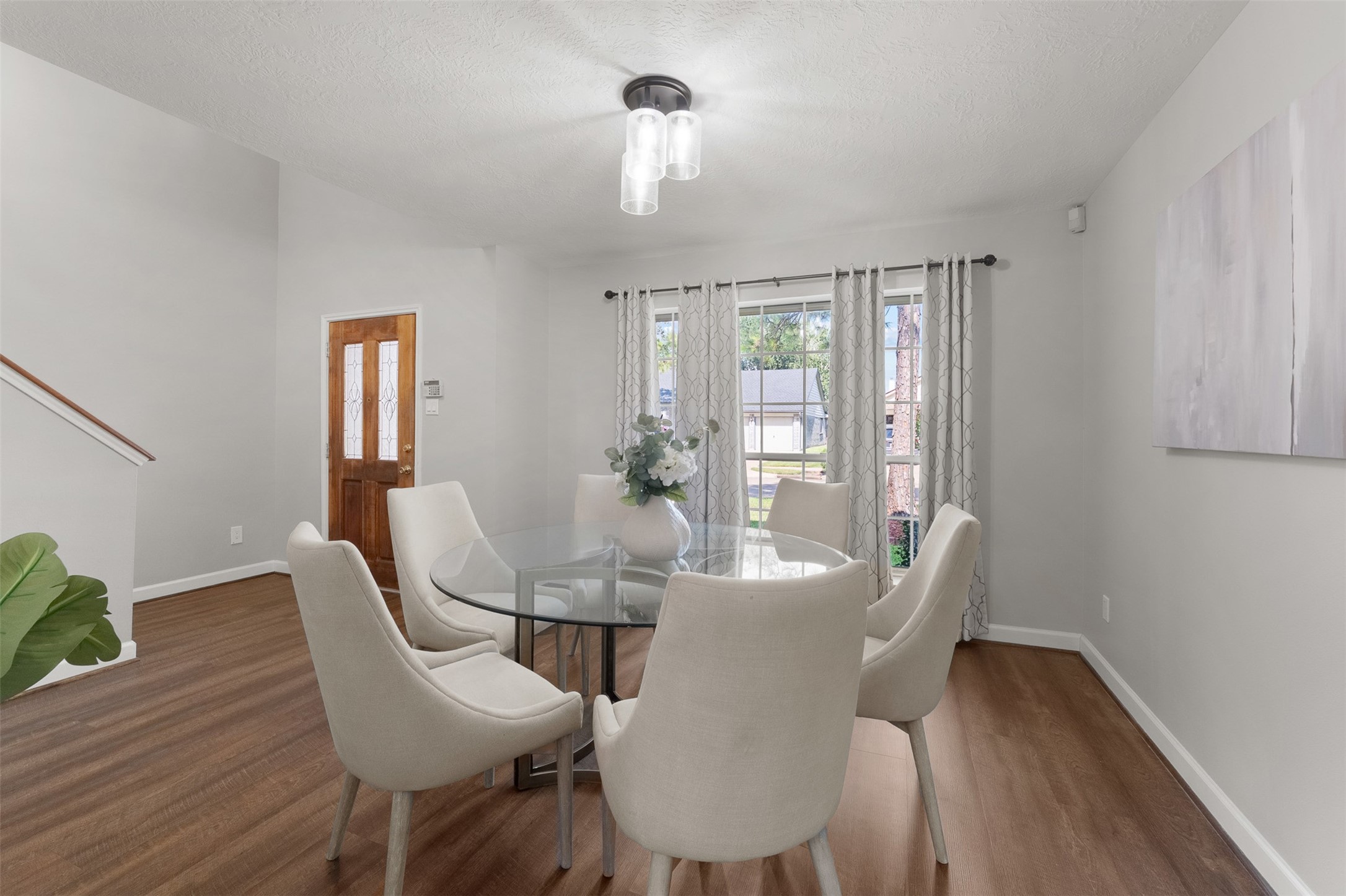 Positioned off the entry, this bright dining area displays rich wood-look floors and neutral walls with high ceilings. Large gridded windows frame neighborhood views, creating a welcoming backdrop for everyday meals and social gatherings.
