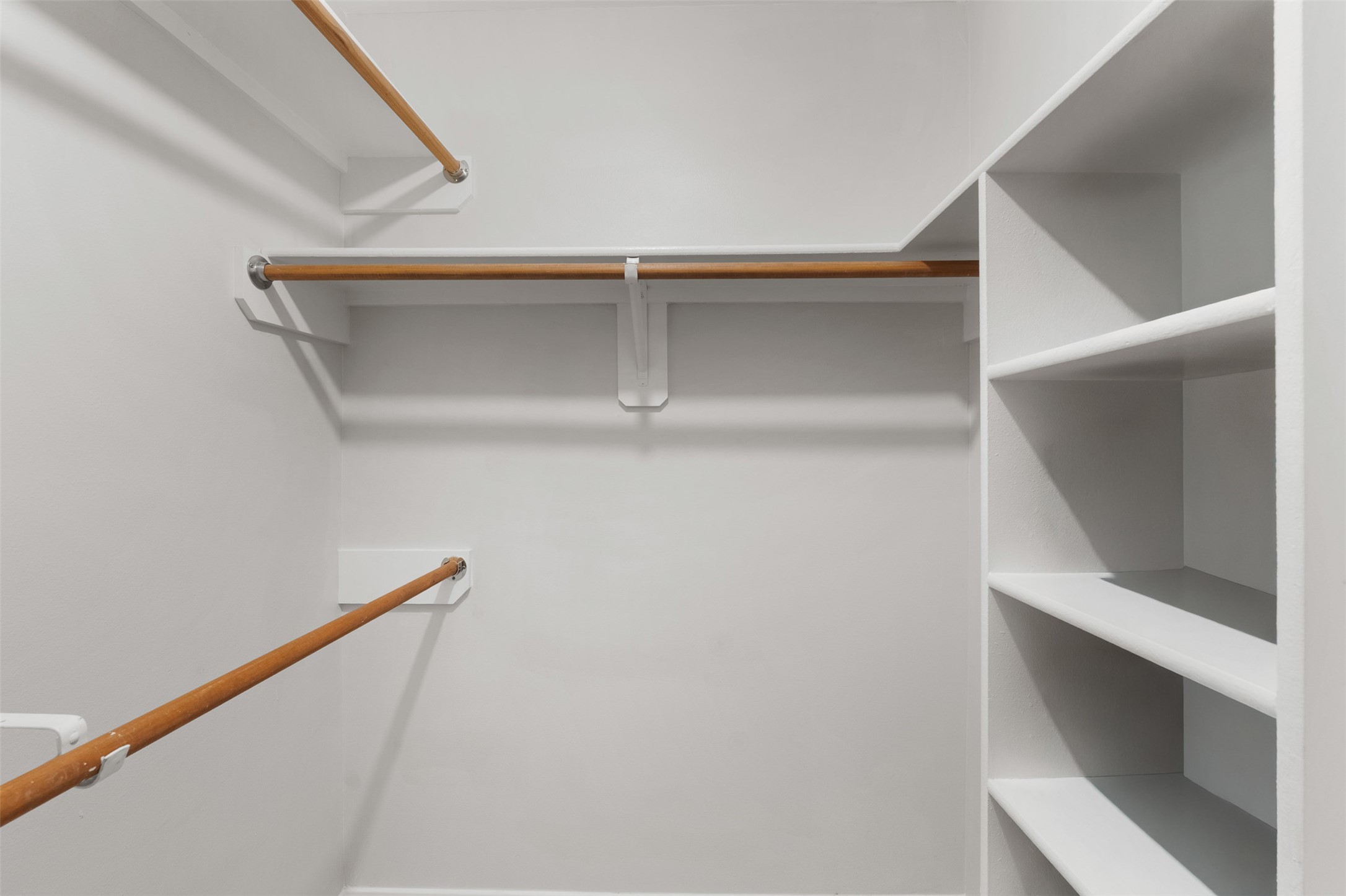 Multi-level wooden hanging rods and built-in shelving maximize organization in this spacious walk-in closet. Fresh interior paint and built-in shelving offer plenty of functional storage space.