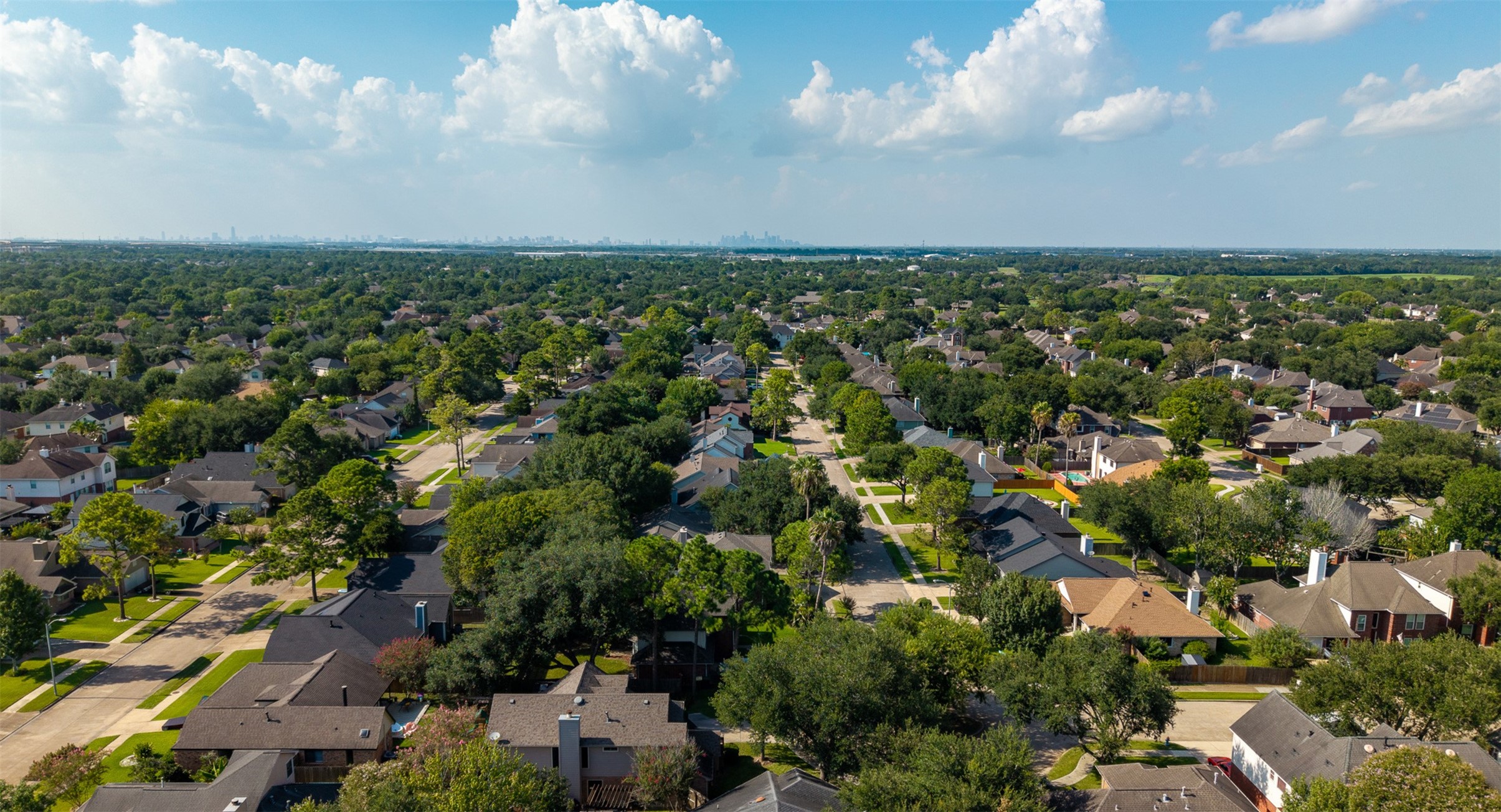 An aerial view captures the vast, tree-canopied neighborhood stretching toward the distant Houston skyline. Convenient access to major thoroughfares ensures a quick commute to the Medical Center alongside proximity to top retail and dining destinations.