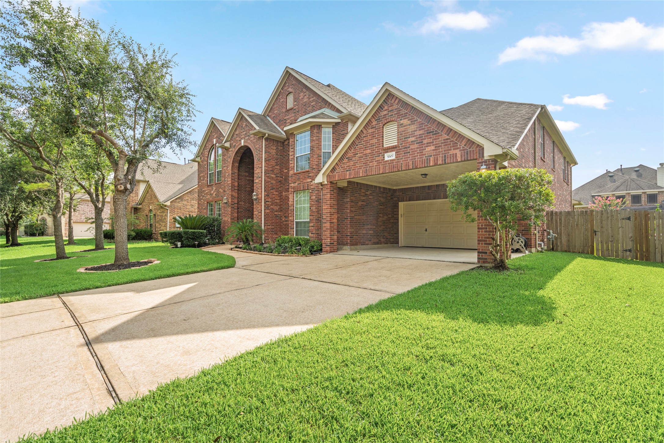 An expansive driveway sweeps toward a rare three-car tandem garage with covered carport, offering exceptional space for vehicles, storage, or a home workshop, practicality meets curb appeal.