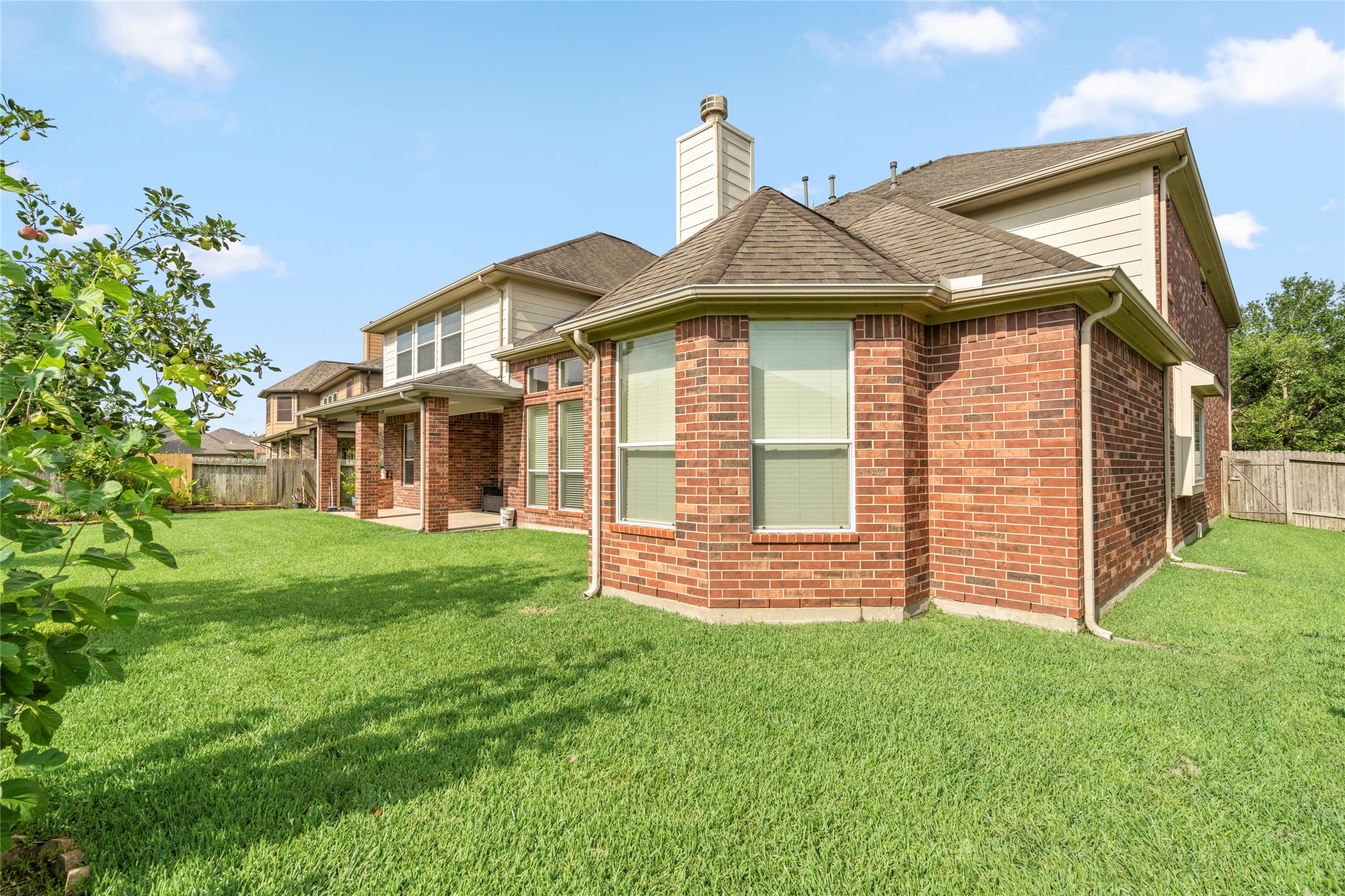 The elegant all-brick exterior continues seamlessly into the backyard, showcasing timeless architecture against a backdrop of manicured greenery.