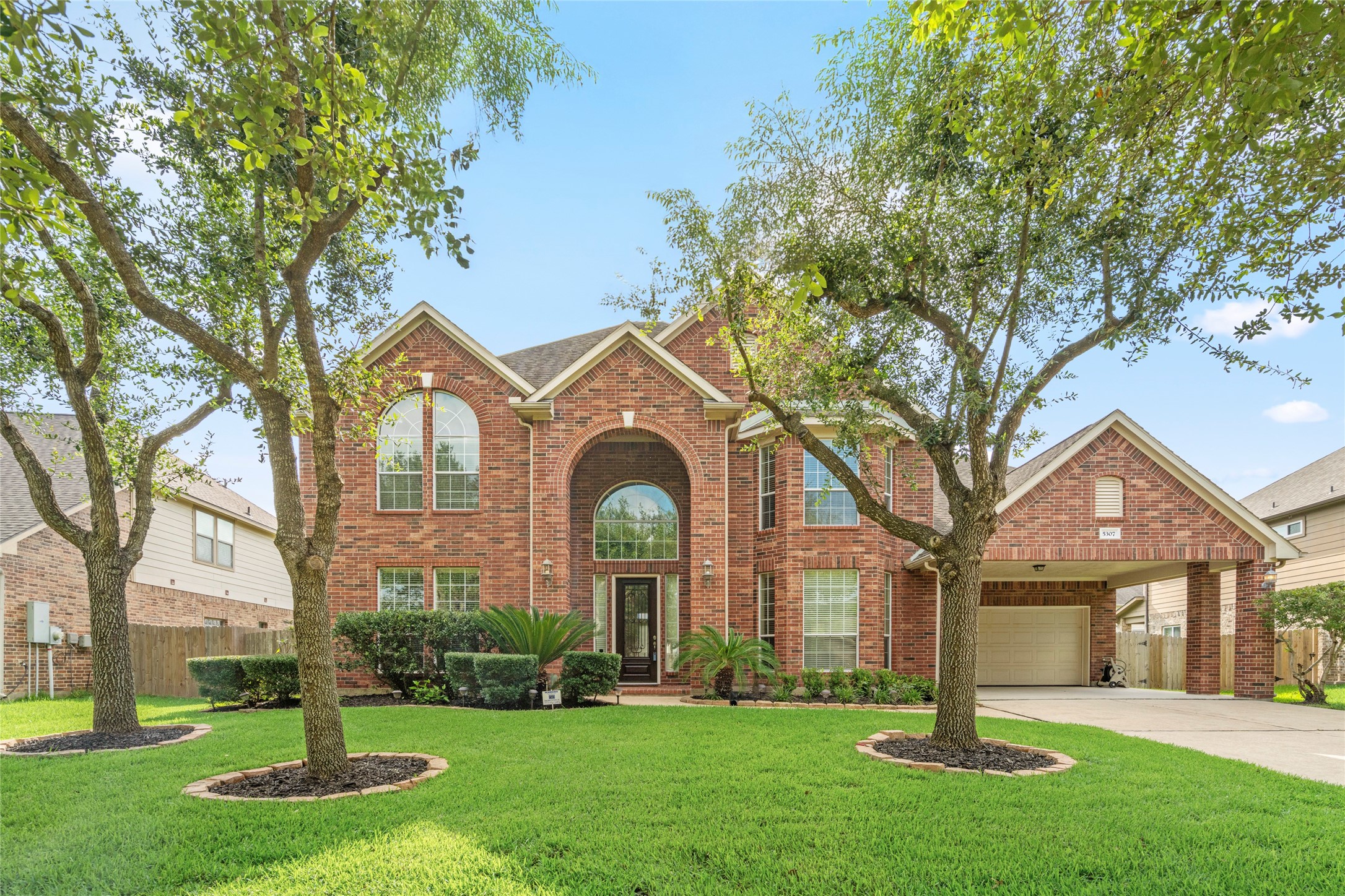 Bathed in daylight, this elegant brick residence showcases manicured landscaping, a grand arched entry, and abundant natural light pouring through oversized windows, a welcoming first impression for the most discerning buyer.
