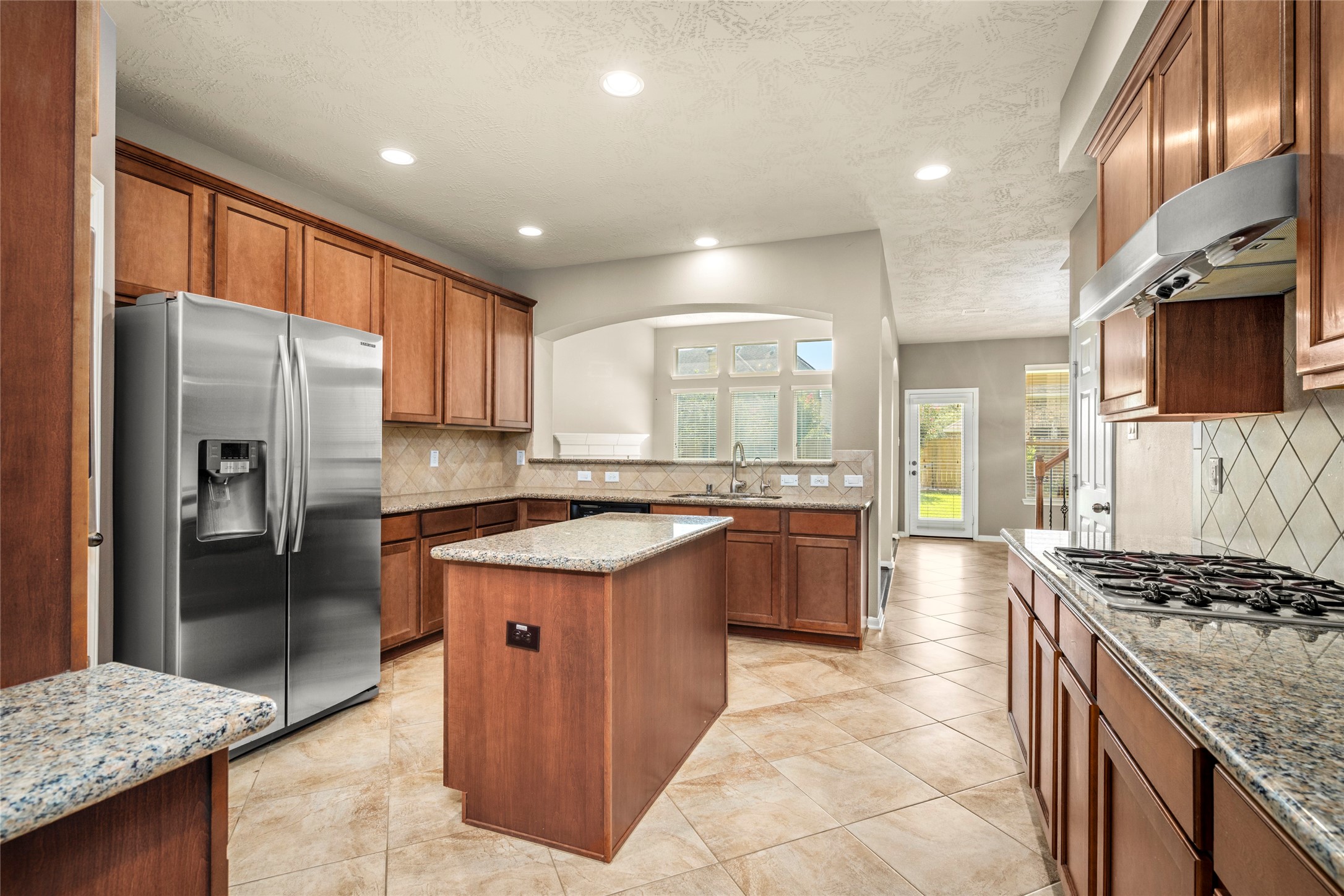 Abundant cabinetry, gleaming granite surfaces, and stainless appliances come together in this beautifully appointed kitchen, ready to inspire countless gatherings and gourmet meals.