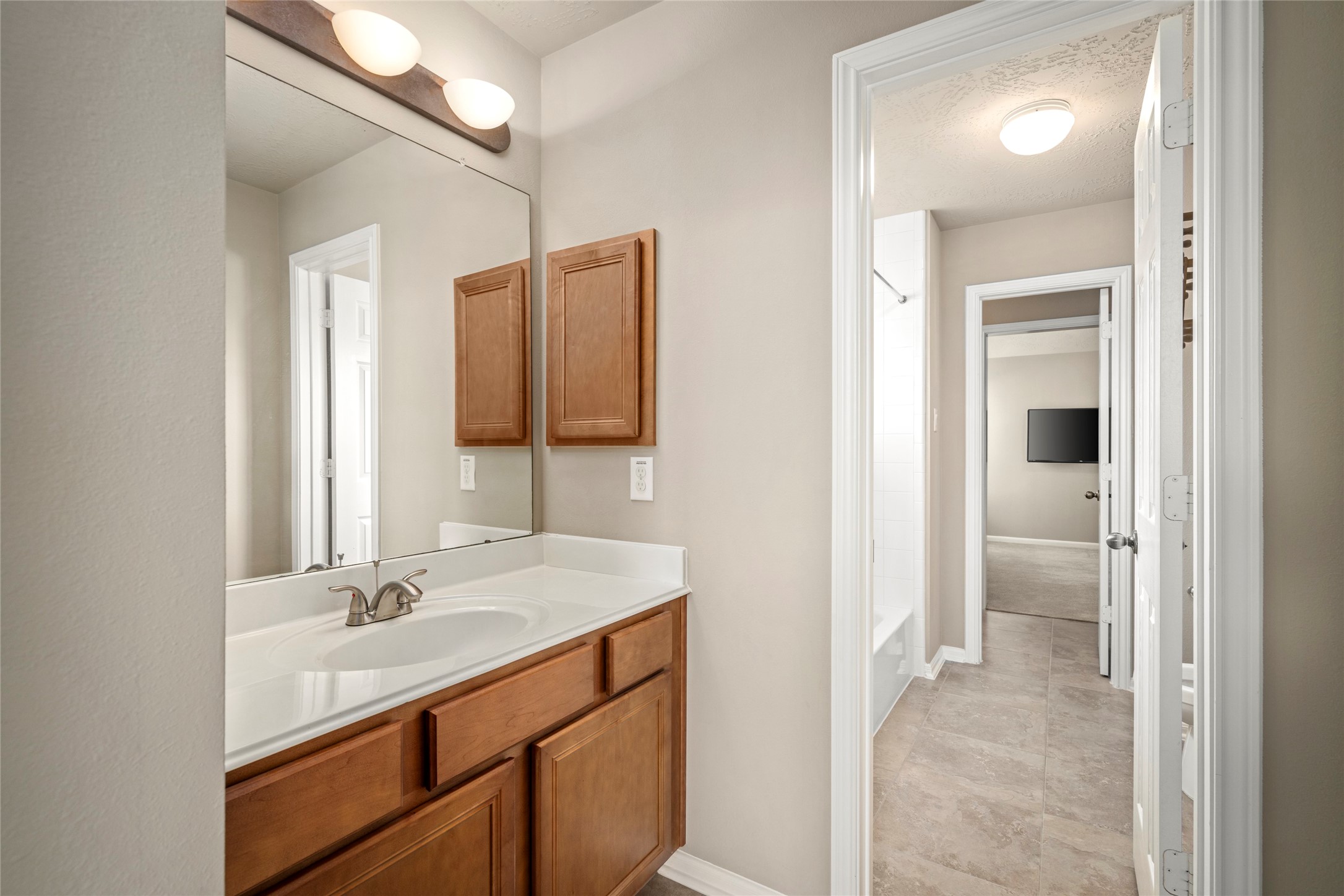 A stylish single-sink vanity bath with a large mirror and modern lighting offers convenient access from the upstairs hallway.