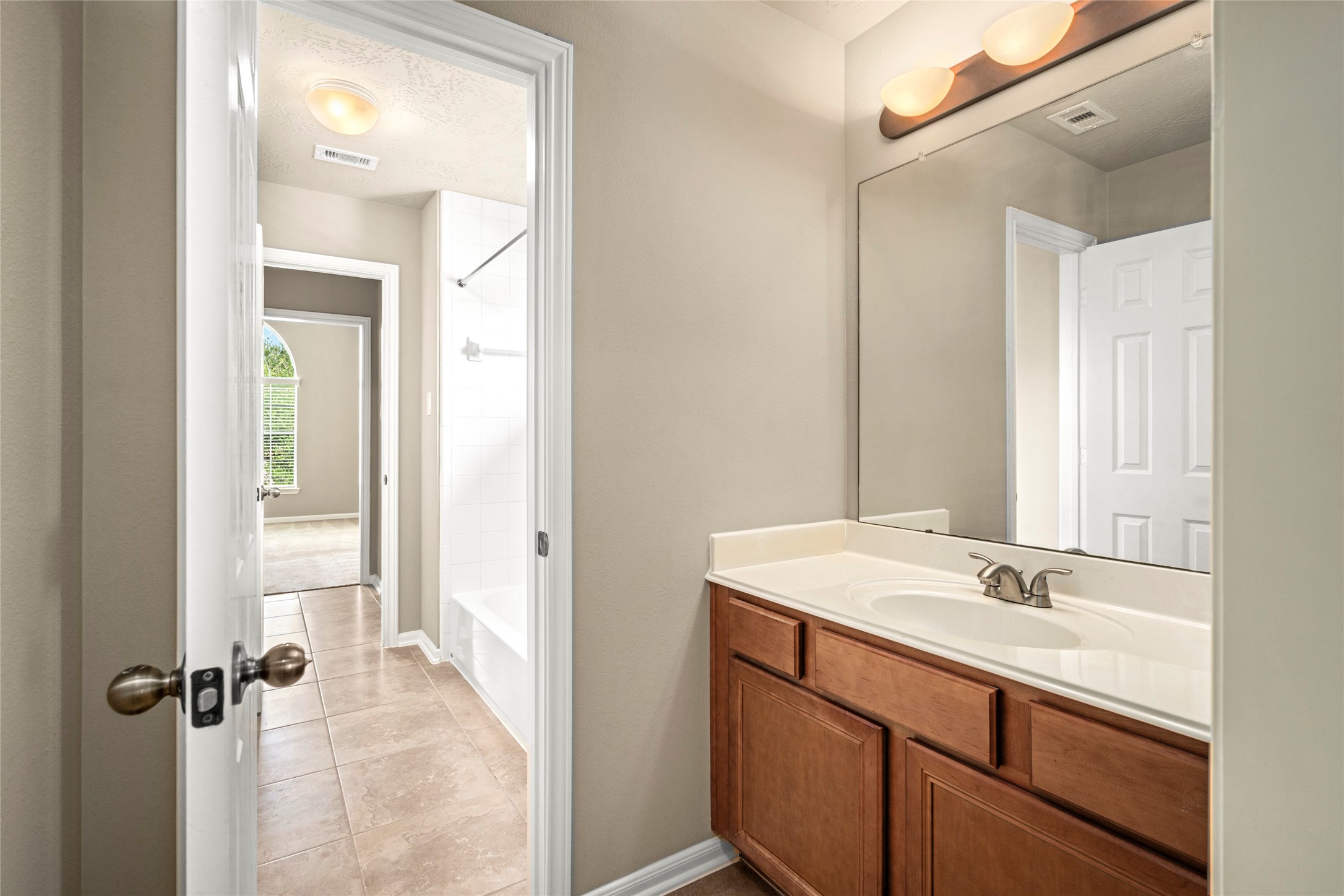 A stylish single-sink vanity bath with a large mirror and modern lighting offers convenient access from the upstairs hallway.