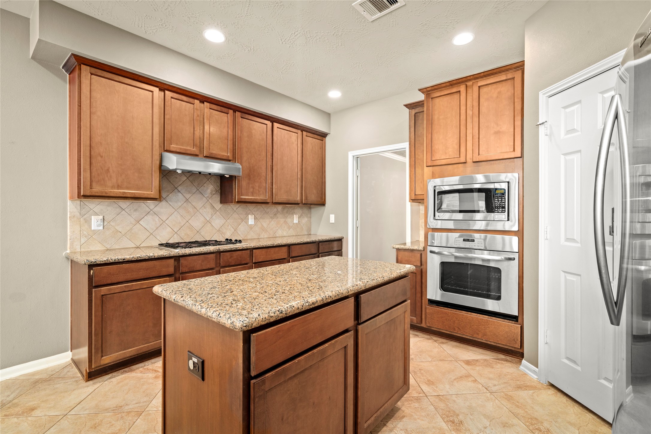 Rich wood cabinetry, granite counters, and a spacious center island define this exceptional kitchen, thoughtfully designed as the true heart of the home.