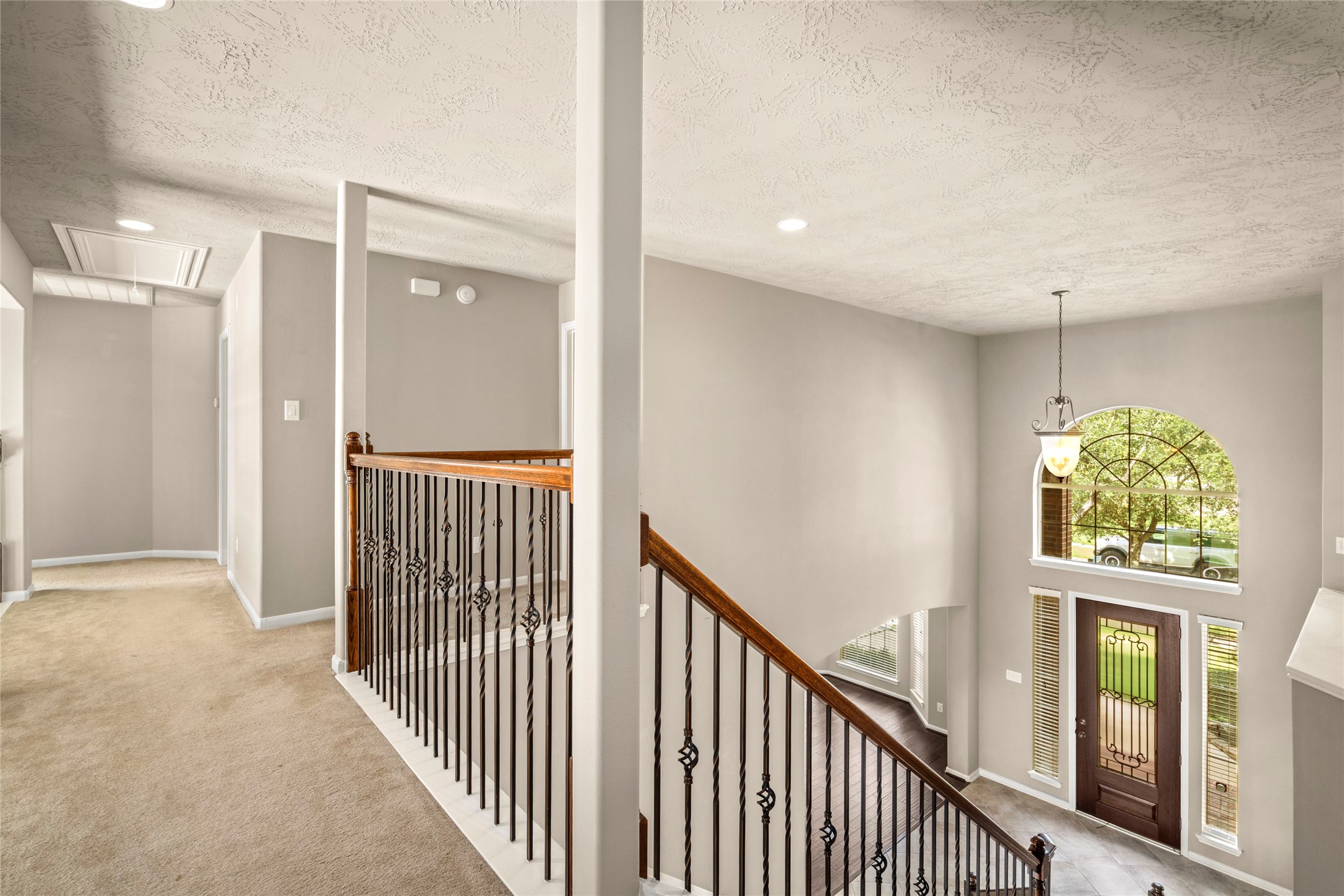 A sleek metal-and-wood railing frames this bright open hallway overlooking the dramatic two-story living area below, an architectural highlight as you make your way to the upstairs retreats.