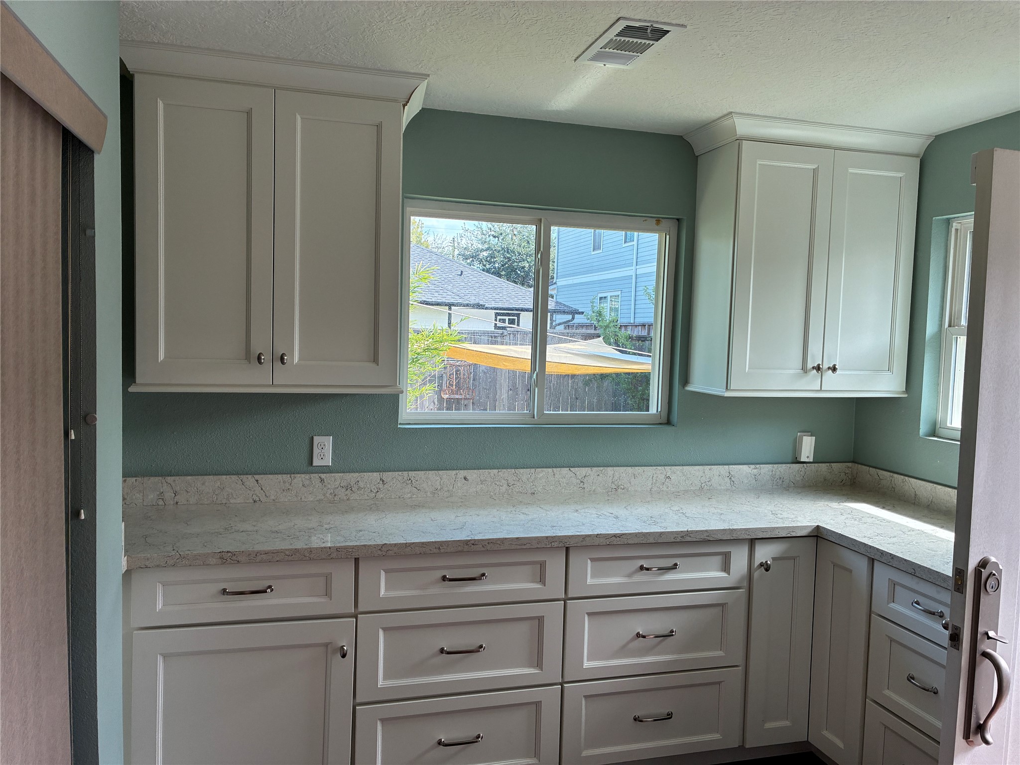 Extensive counter space and cabinetry adjacent to washer/dryer storage area.
