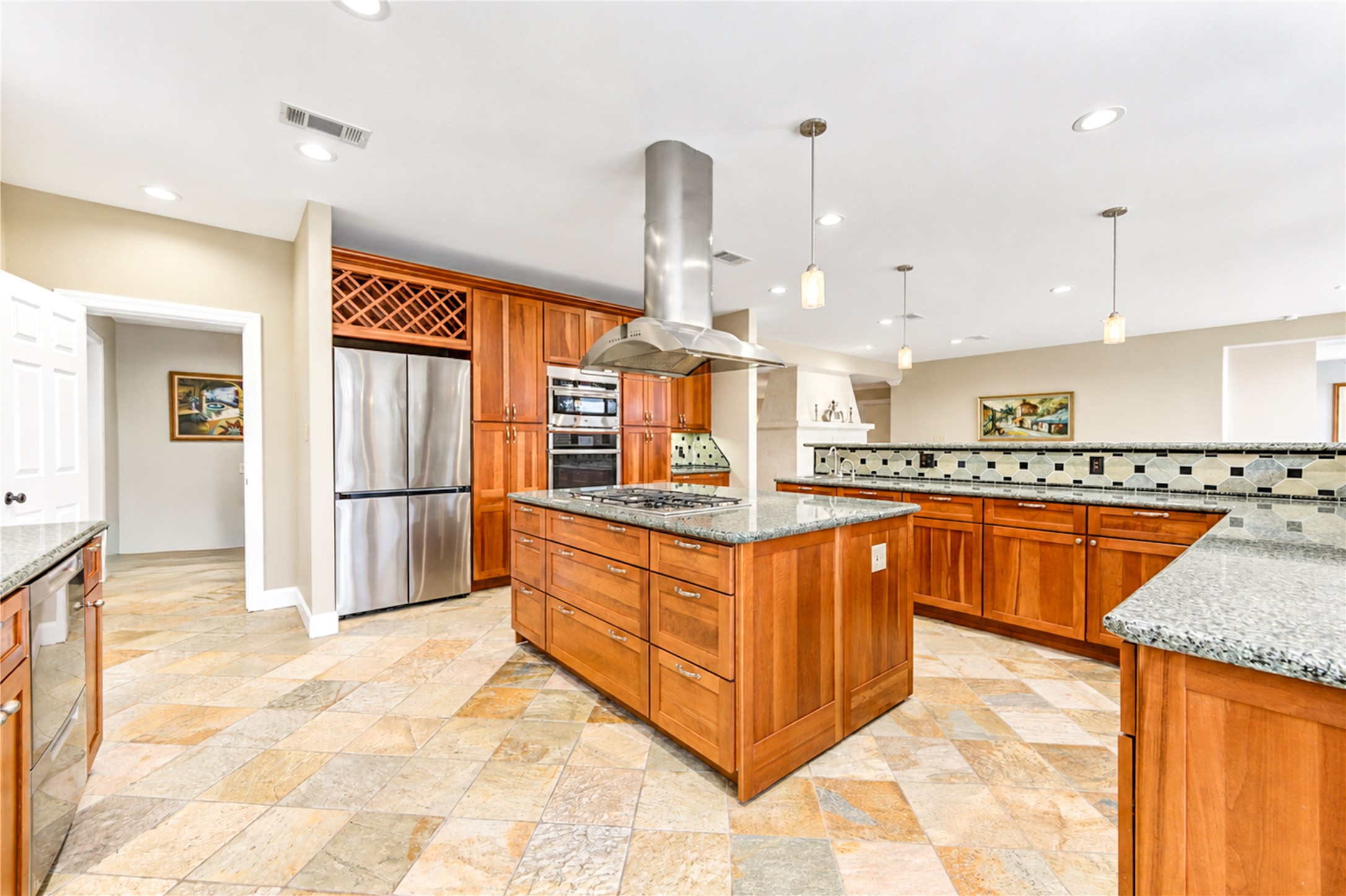 The kitchen opens to the family room, with built-in double ovens, a wine rack and a gas cooktop island beneath the vent hood.