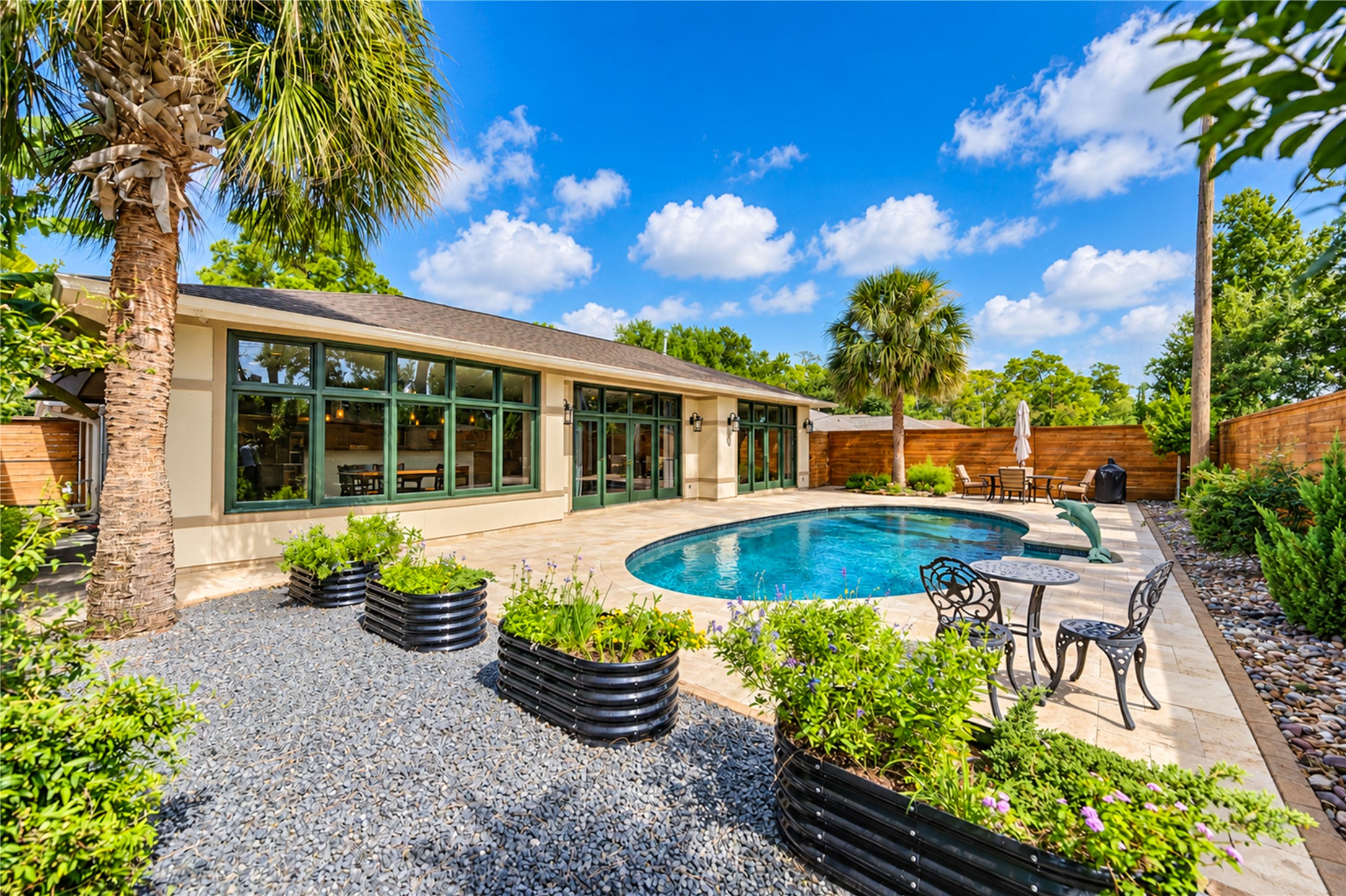Expansive glass opens the rear of the home to the pool, the travertine terrace and raised garden planters.