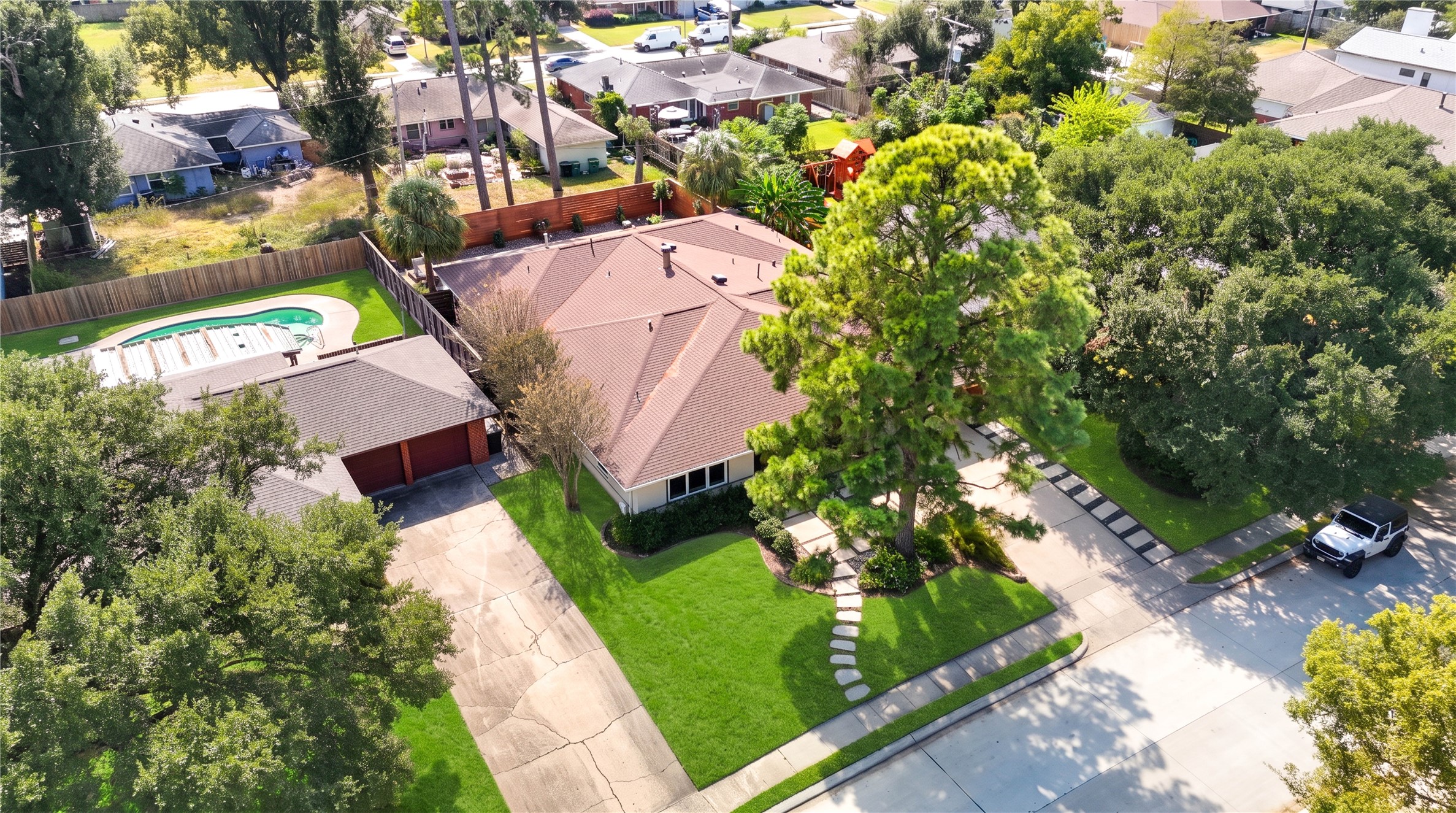 An aerial view from the front shows the home's single-story footprint, landscaped lot and mature trees.