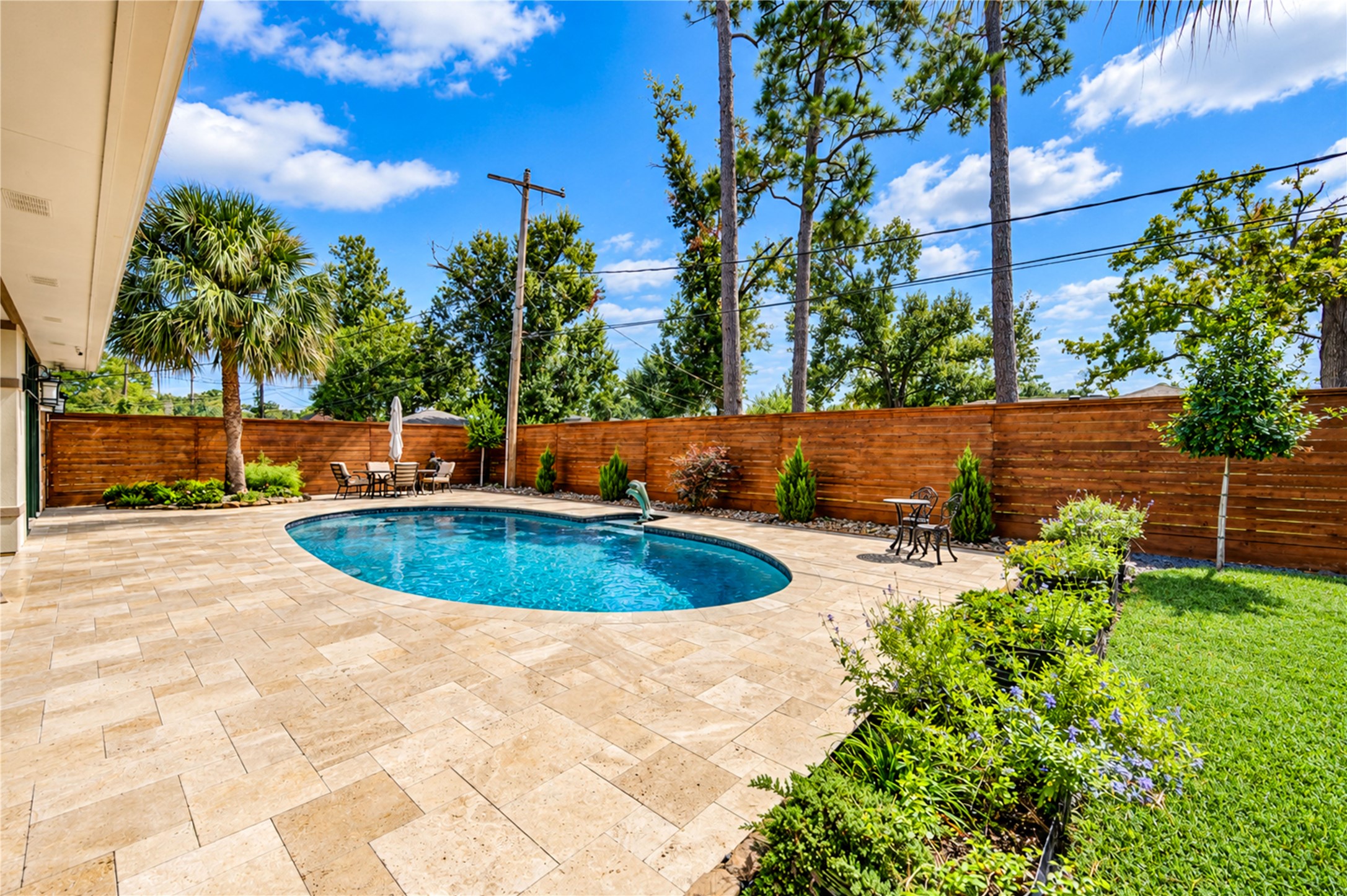 Palms, landscaped beds and a travertine terrace surround the pool along the rear of the home.