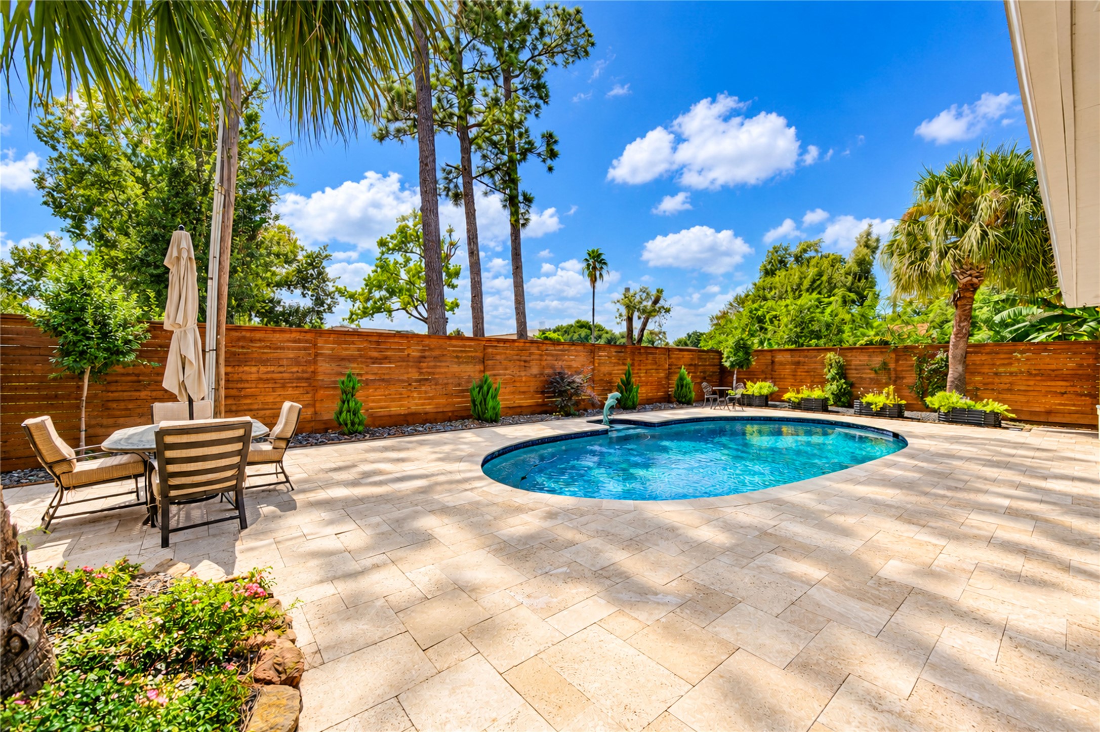 A generous poolside terrace, mature palms and a horizontal wood privacy fence complete this inviting outdoor retreat. A generous poolside terrace, mature palms and a horizontal wood privacy fence complete this inviting outdoor retreat.