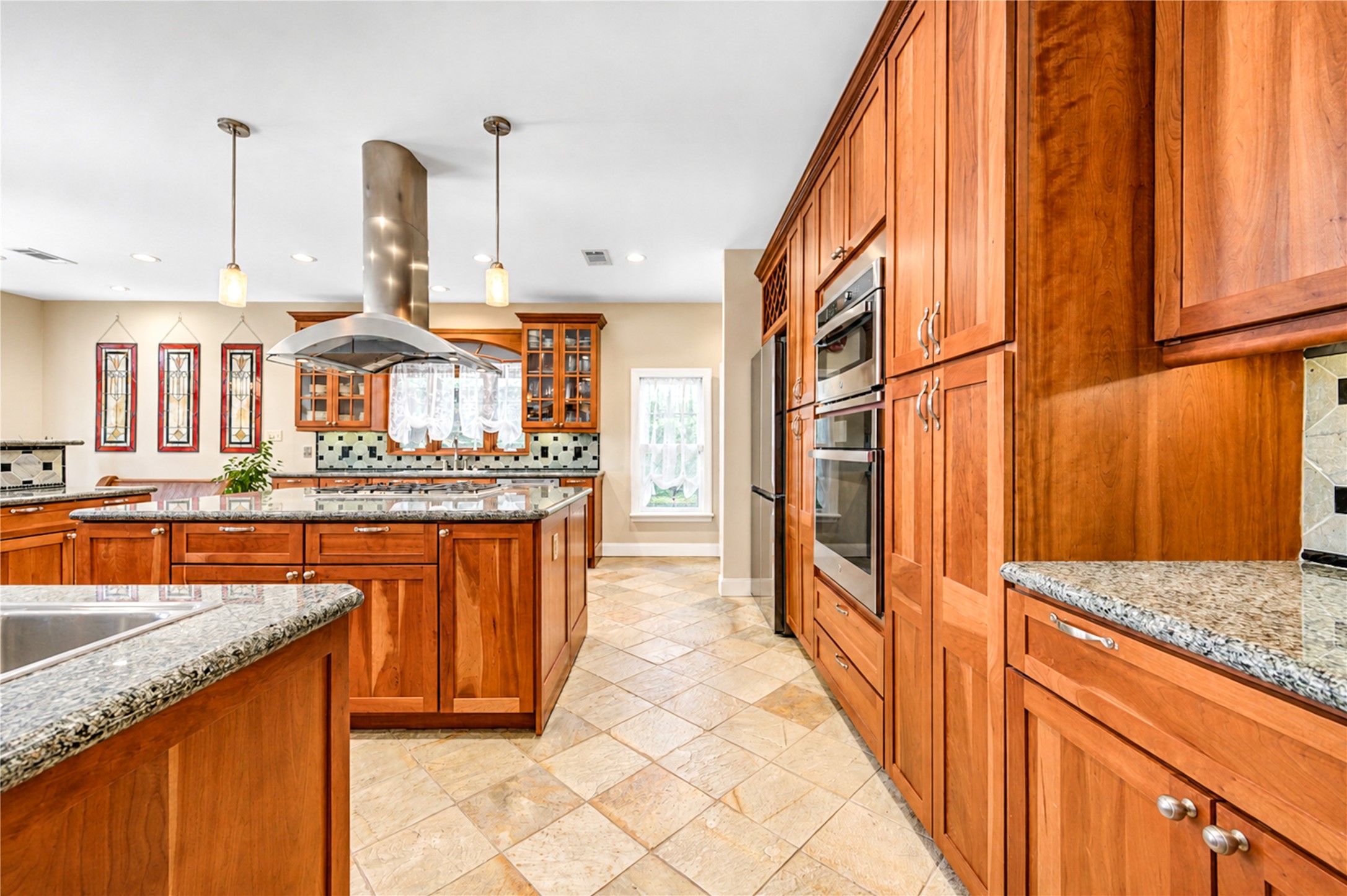 Stone flooring, a chandelier and a corner of wood-framed windows make the breakfast nook a bright setting beside the pool.