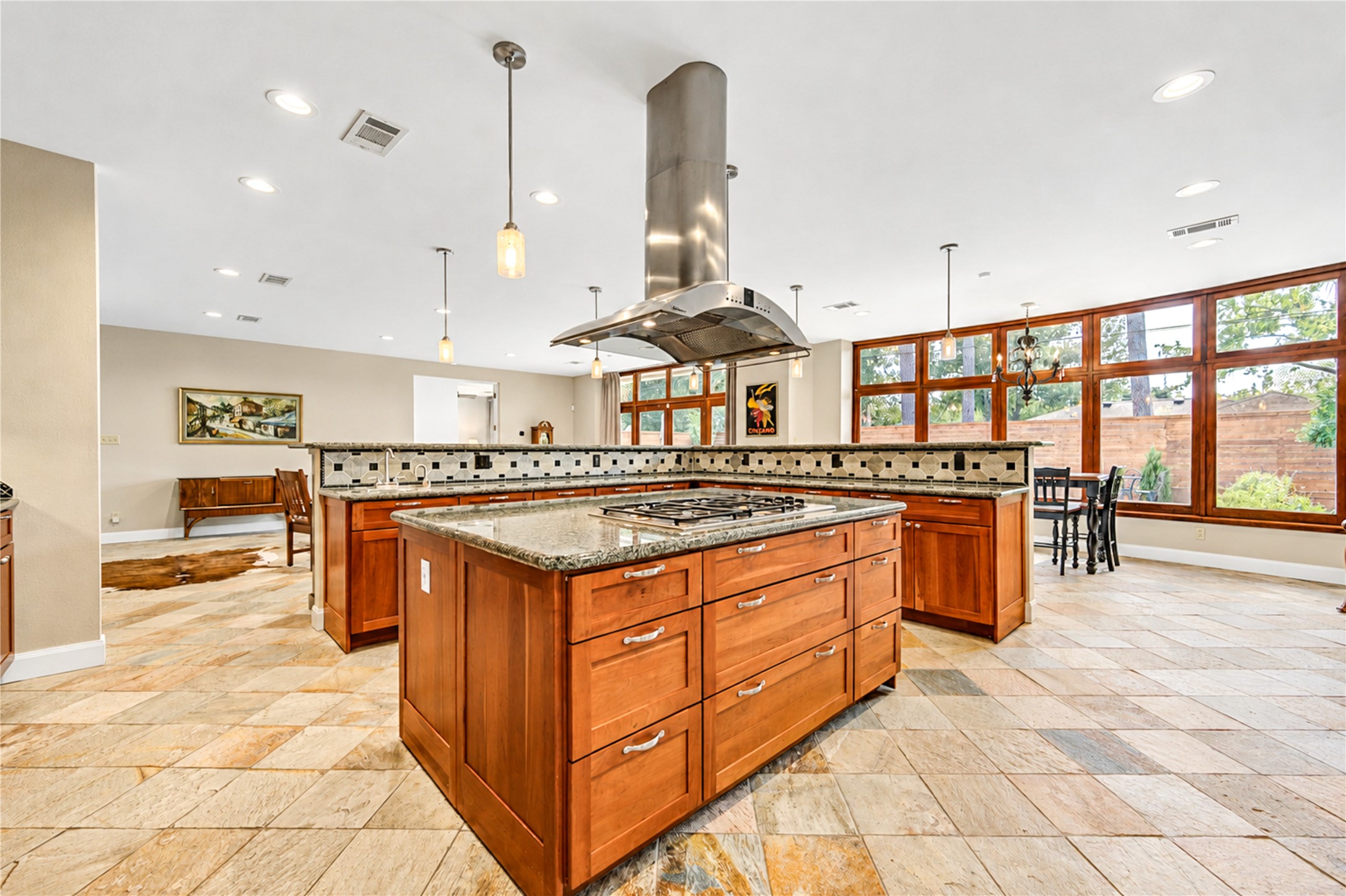 Two generous islands, granite countertops, rich wood cabinetry and a statement vent hood distinguish the light-filled kitchen.