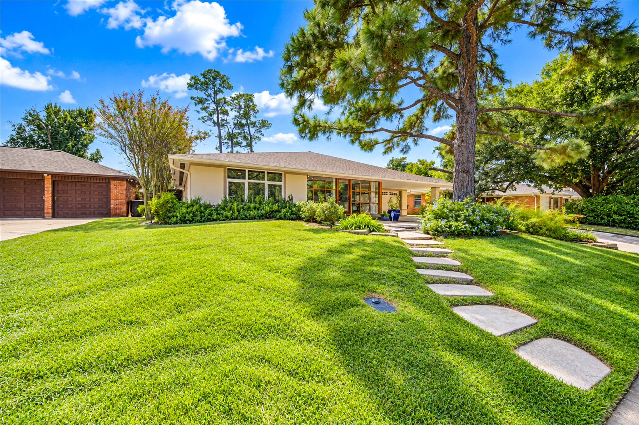 A glass-and-wood entry and a geometric concrete-and-gravel drive set an architectural tone beside the attached garage. A glass-and-wood entry and a geometric concrete-and-gravel drive set an architectural tone beside the attached garage.
