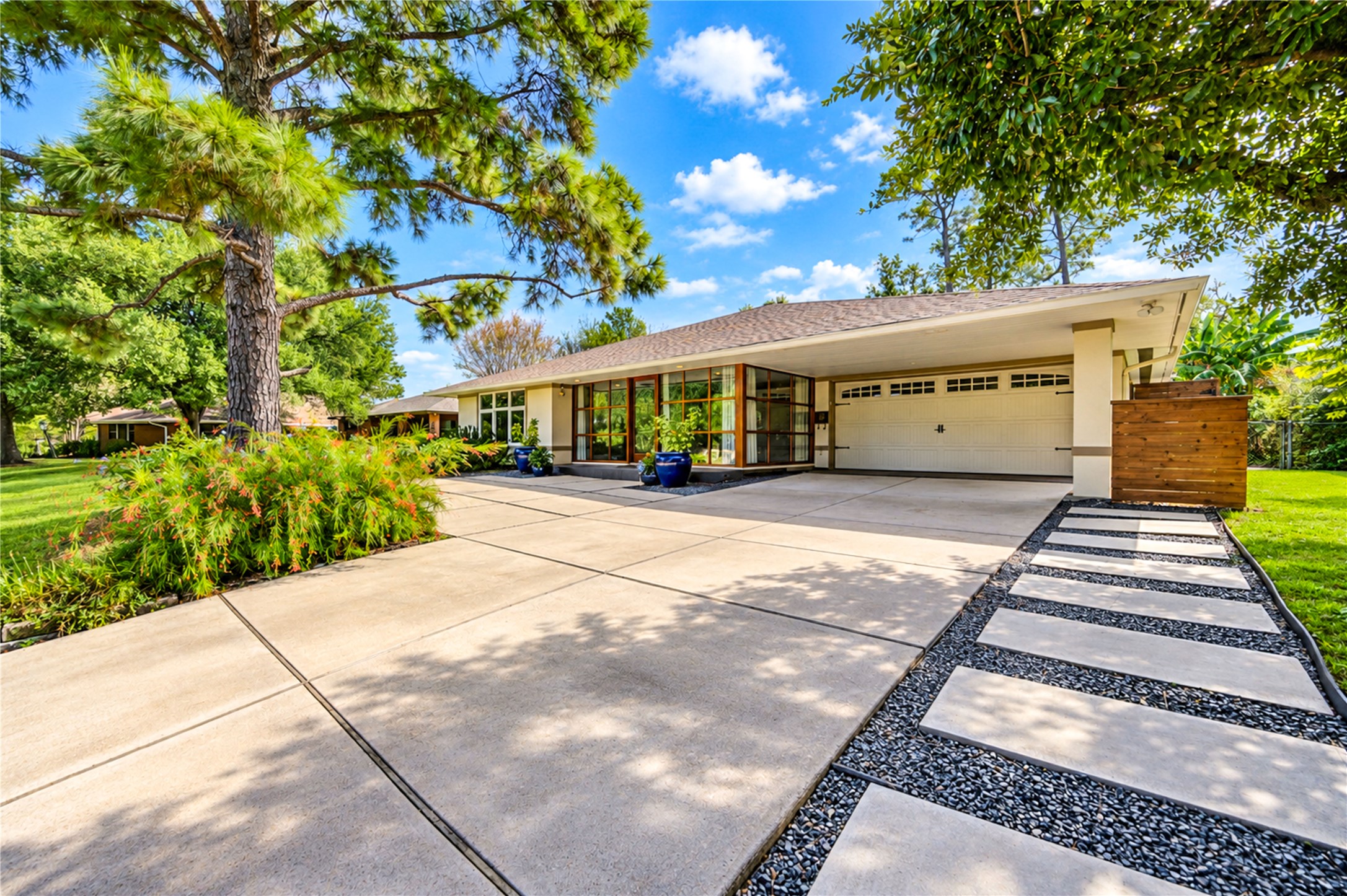 A low roofline, wood-framed glass entry and stepping-stone path set a clean mid-century tone at the front of the home. A low roofline, wood-framed glass entry and stepping-stone path set a clean mid-century tone at the front of the home.
