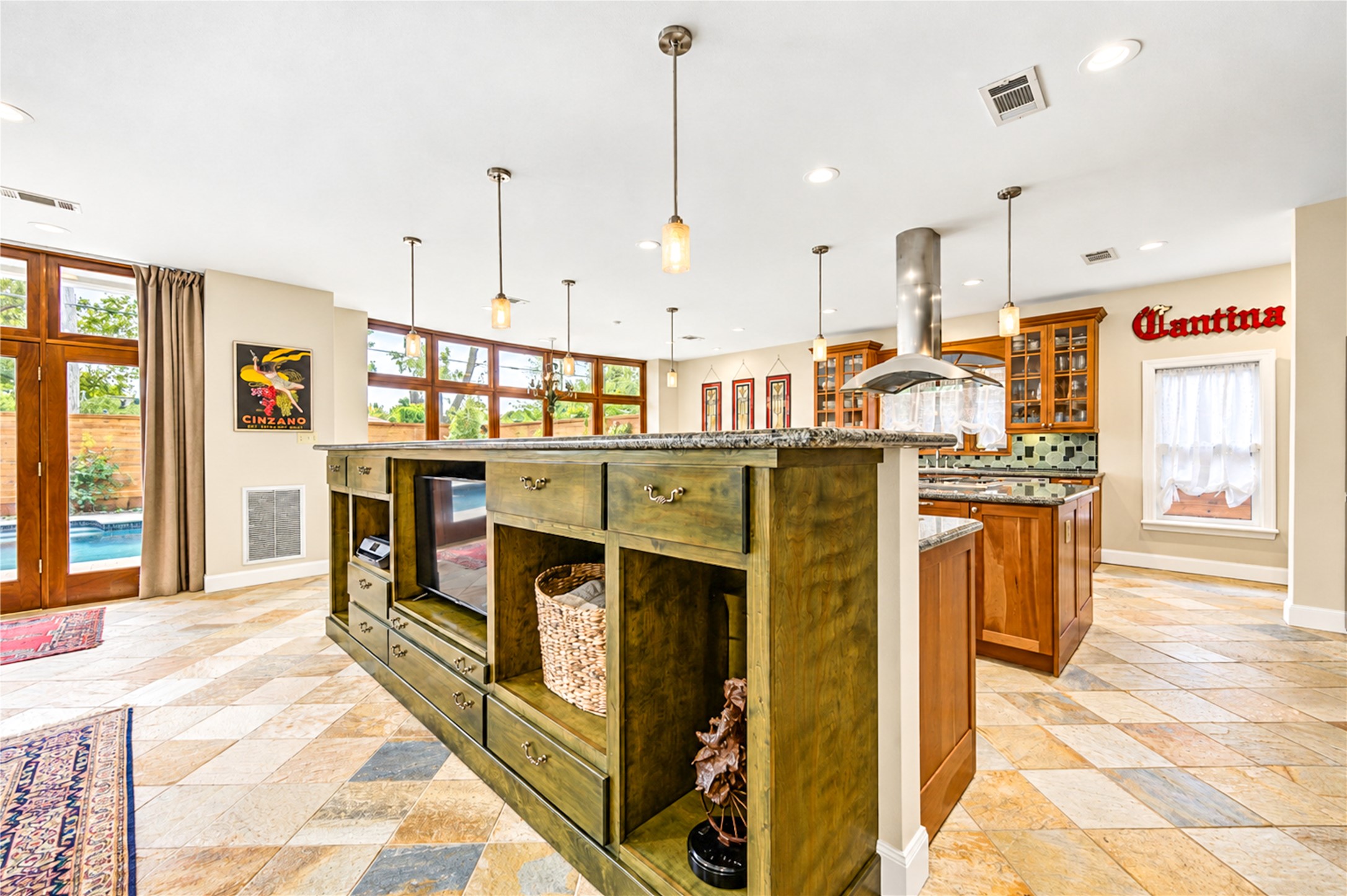Stone flooring, rich wood cabinetry and an open plan join the family room and kitchen in one light-filled space.