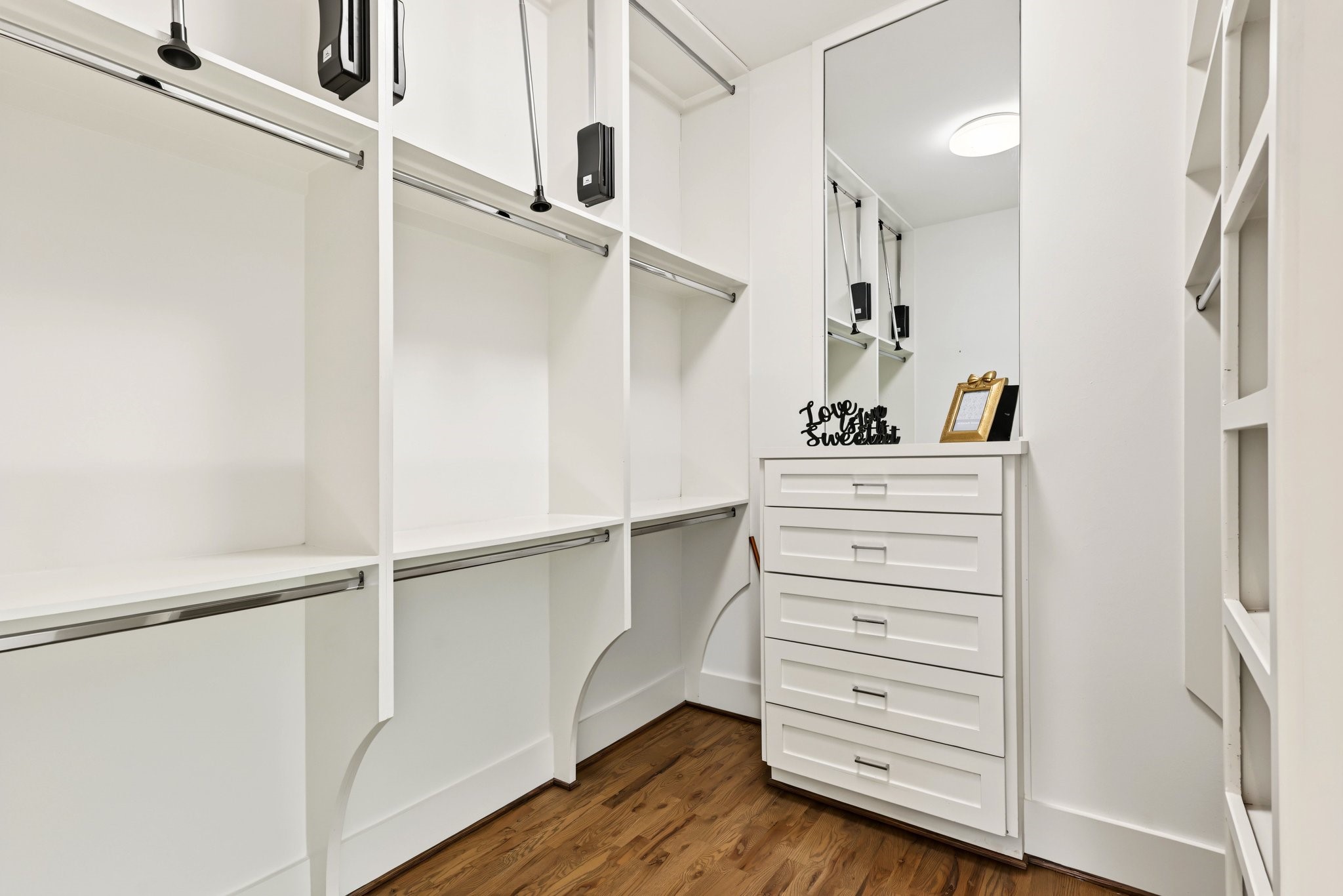Bring boutique-style organization home in this expansive primary walk-in closet. Tailored with custom white built-ins, abundant open shelving, and multi-tier hanging rodscomplete with pull-down upper railsthe space maximizes vertical storage for a meticulously curated wardrobe of clothing, footwear, and accessories.