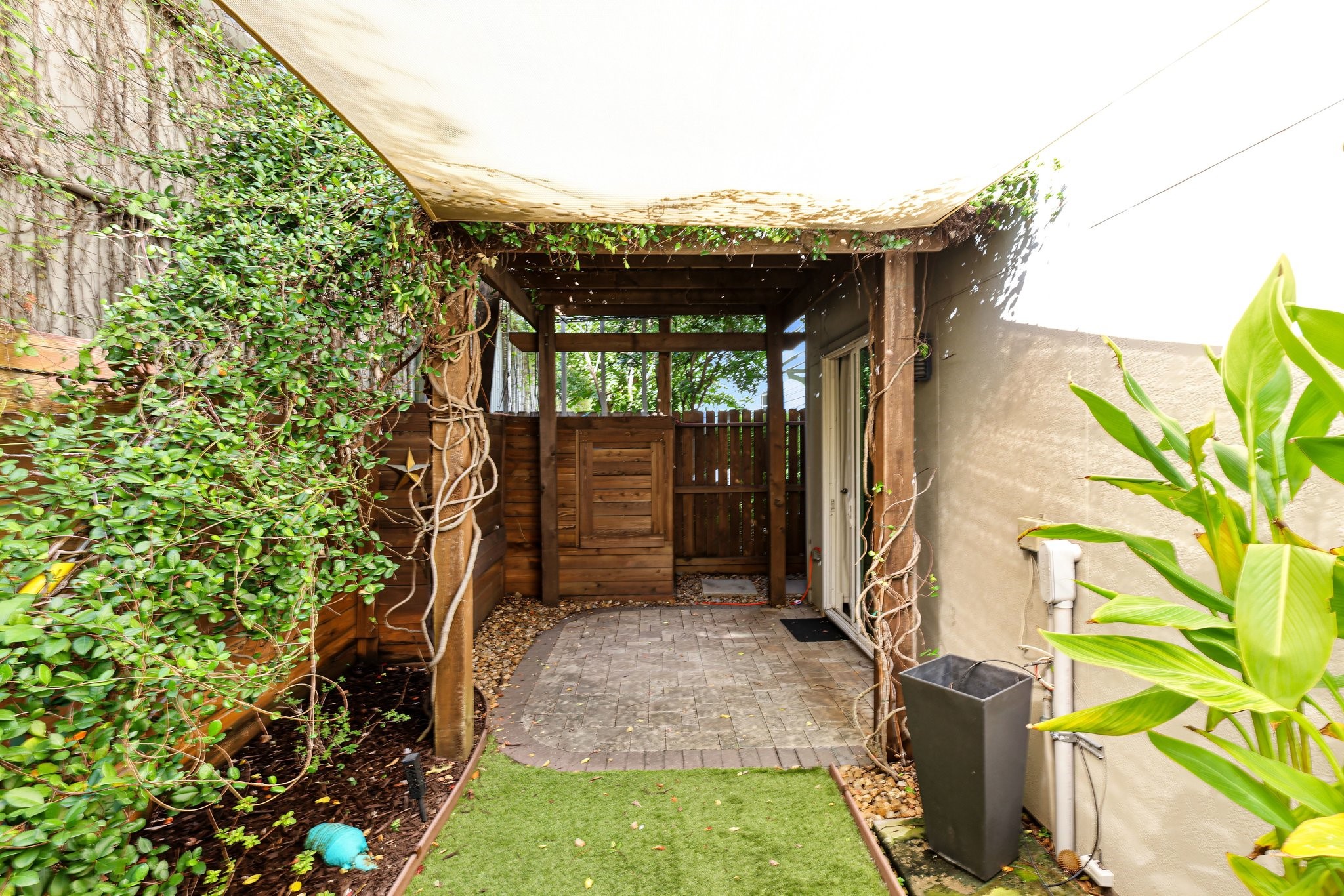 Morning espresso and unhurried evening drinks feel right at home beneath the vine-draped pergola and architectural shade sail. Add a chic bistro set or outdoor lounge seating to effortlessly personalize this inviting private courtyard retreat.
