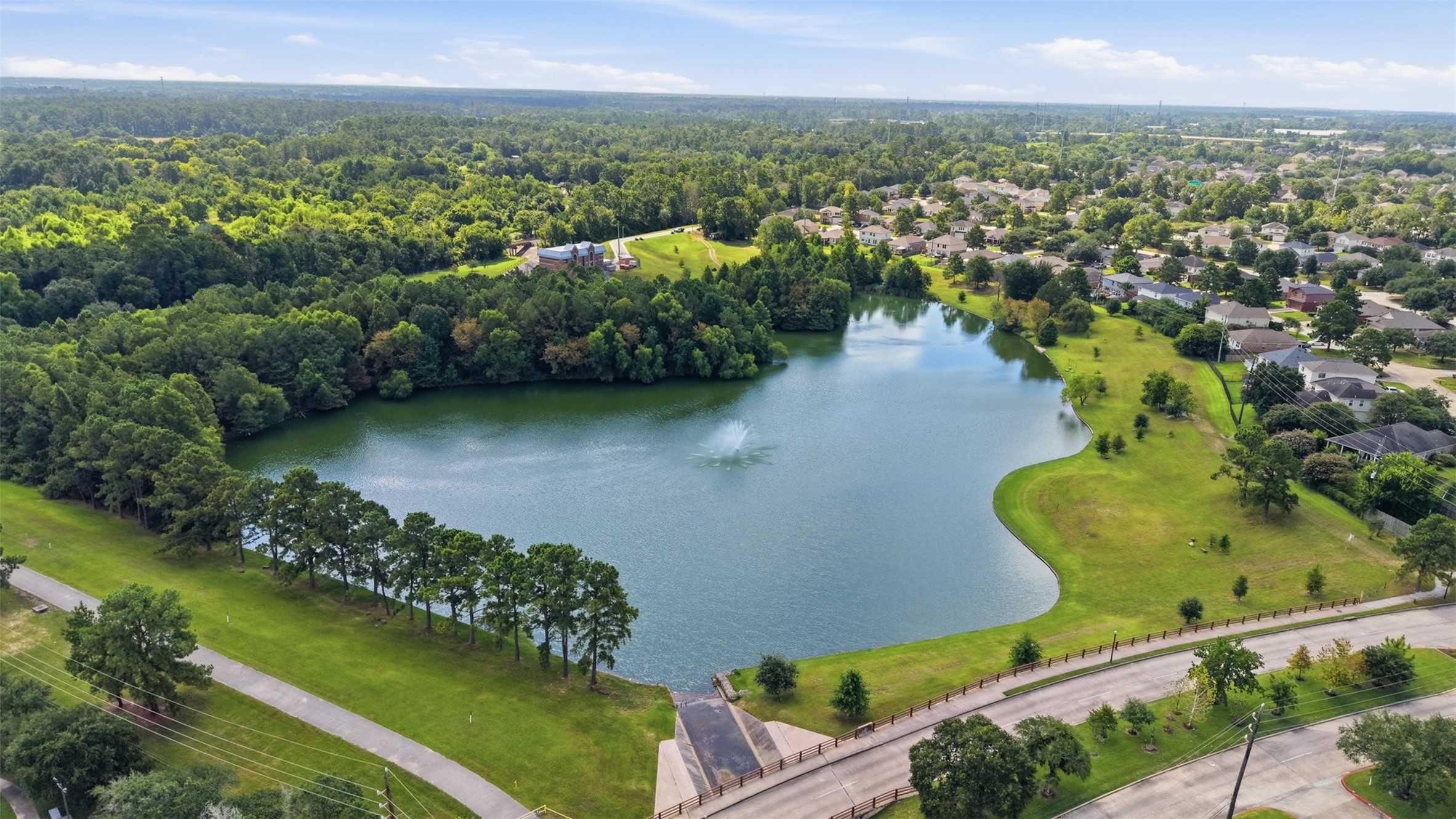 Stunning aerial view of the community's centerpiece retention lake, featuring a central water fountain, surrounding greenbelts, and paved walking paths.