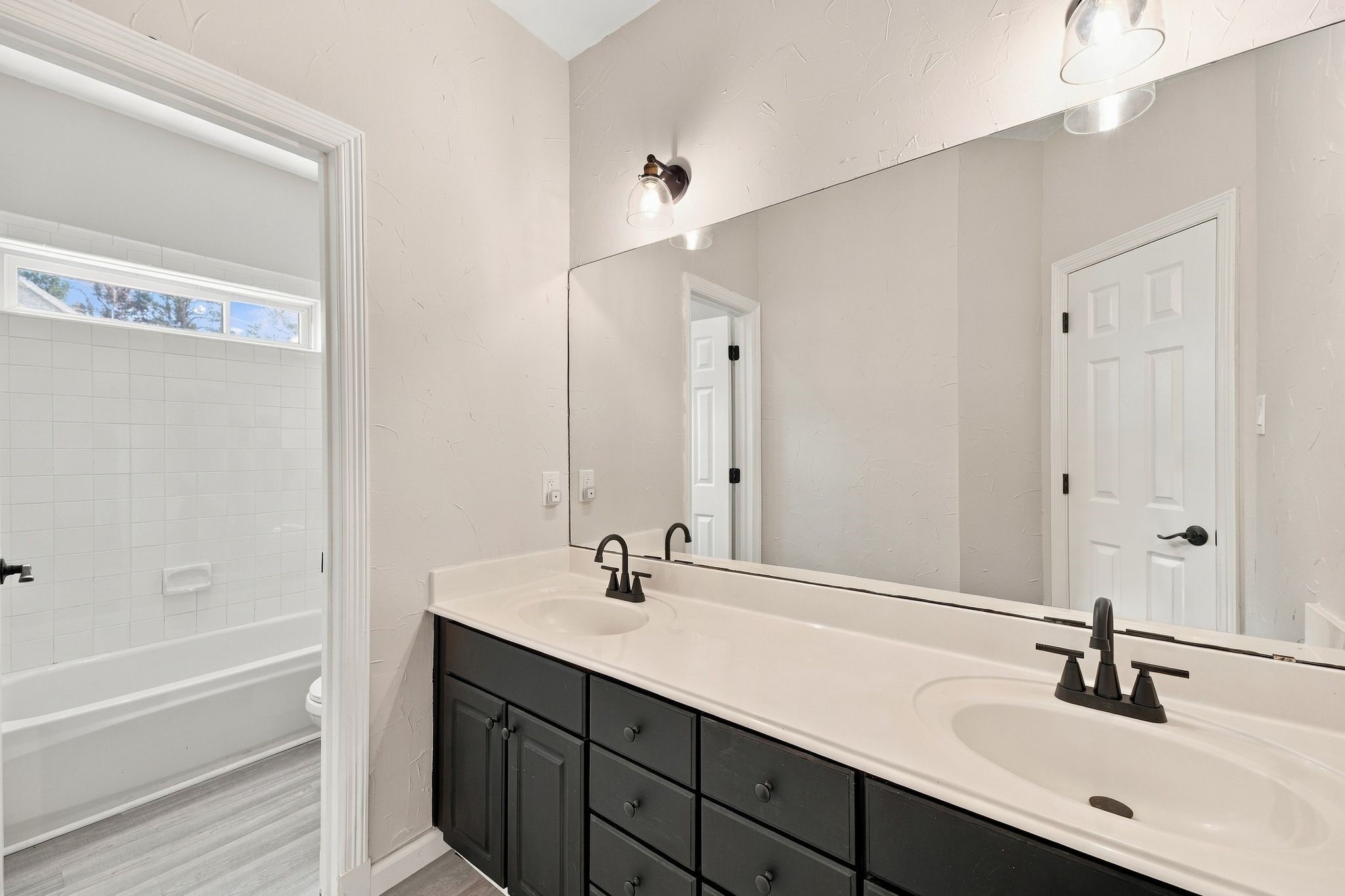 This secondary full bath is located upstairs and is shared by the three secondary bedrooms. Notice the two sinks and large vanity! The updated lighting and hardware are so pretty too!