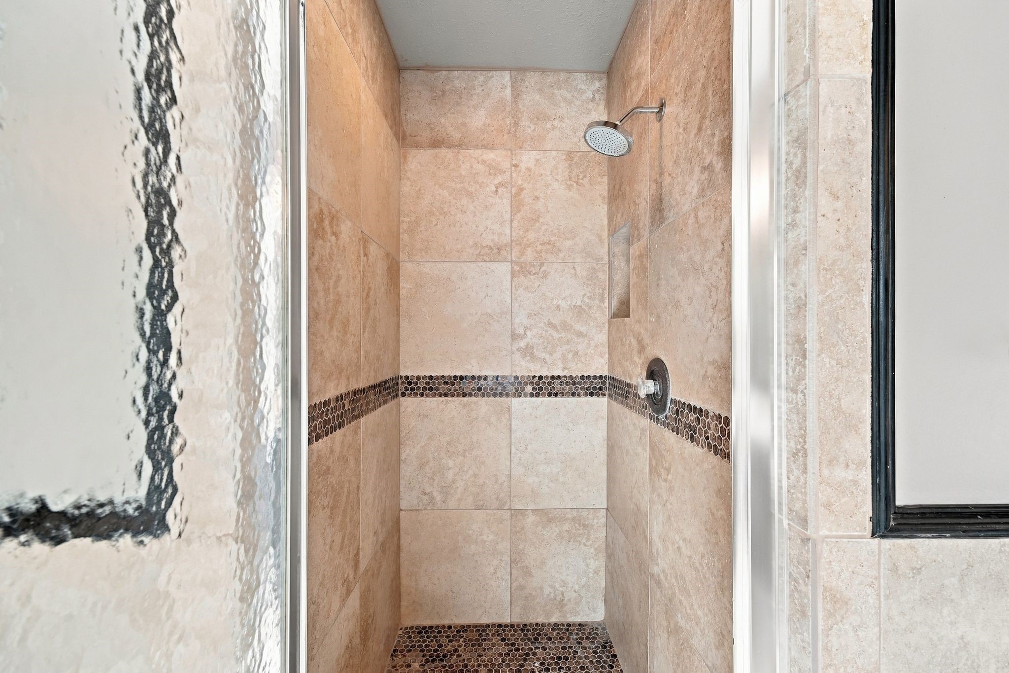 Updated tile stand alone shower with glass door in primary ensuite bath.