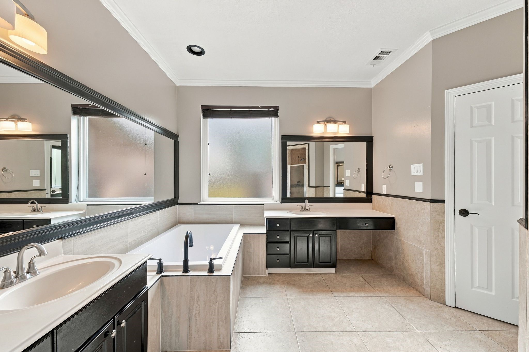 The primary bath has updated framed mirrors and lighting, a recently replaced soaking tub, gorgeous tile floors and TWO sinks!