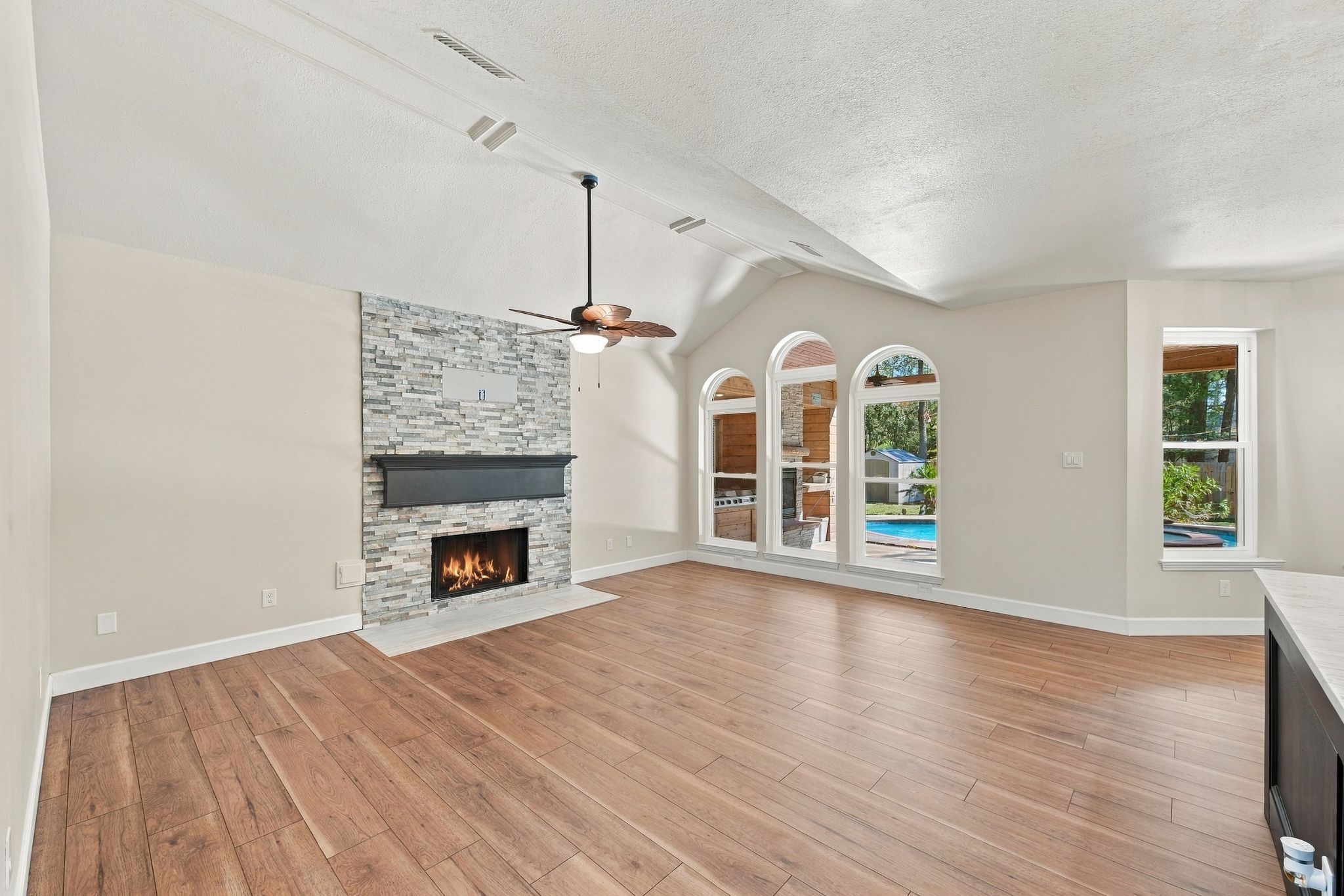 The large living room which is open to the kitchen and living room has a beautifully updated stacked stone fireplace with gas logs, a recently replaced ceiling fan and updated flooring.