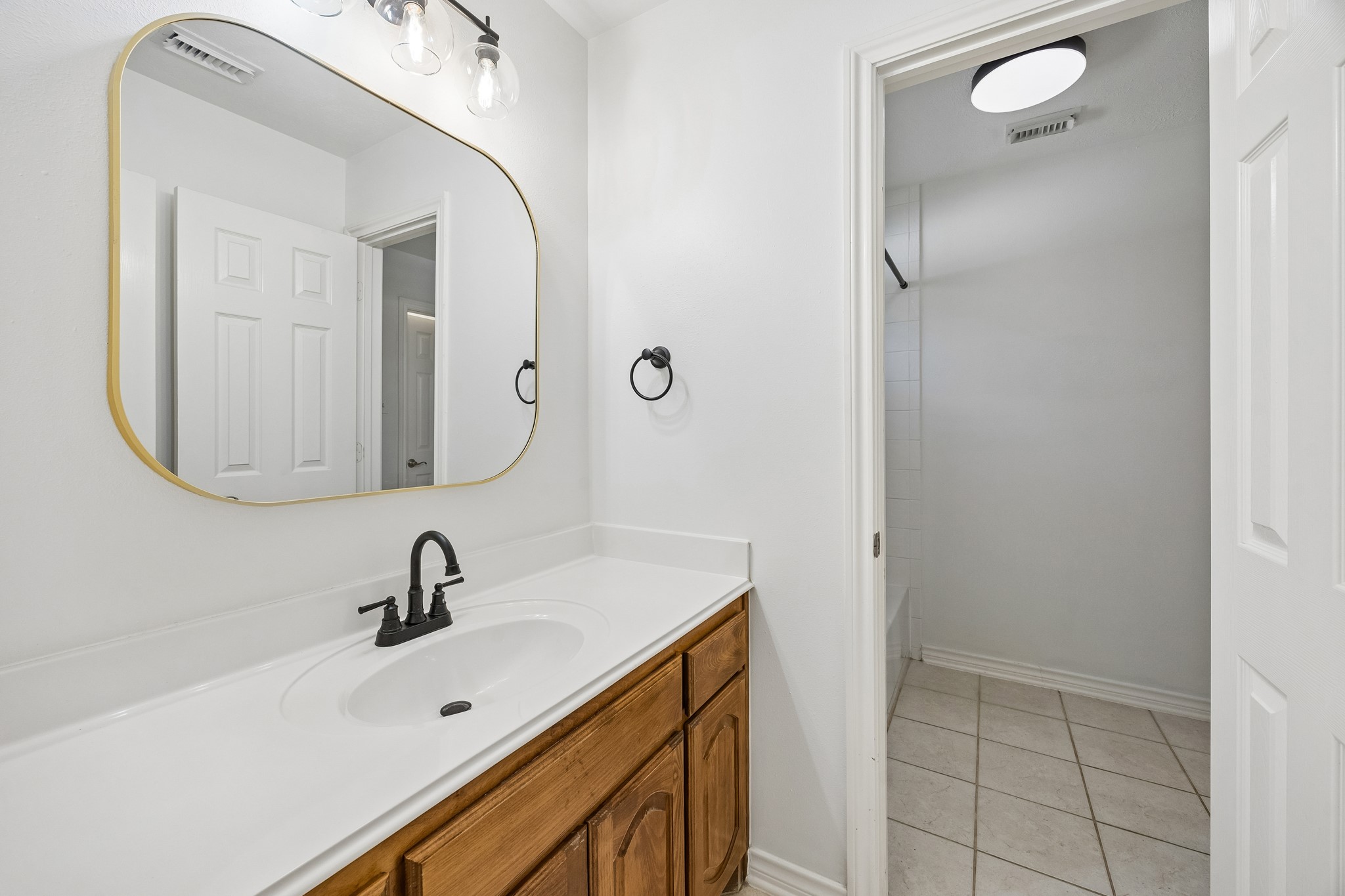 The second private vanity area of the Jack-and-Jill bath provides added convenience between two secondary bedrooms, featuring its own sink, generous counter space, updated fixtures, and direct access to the shared bath area.