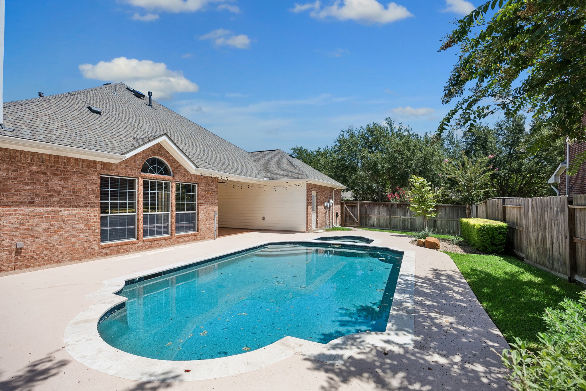 Another view of the private backyard oasis highlights the sparkling updated pool, generous poolside space, mature landscaping, and added privacy, creating an ideal setting for outdoor entertaining, relaxing, and enjoying sunny Texas days.