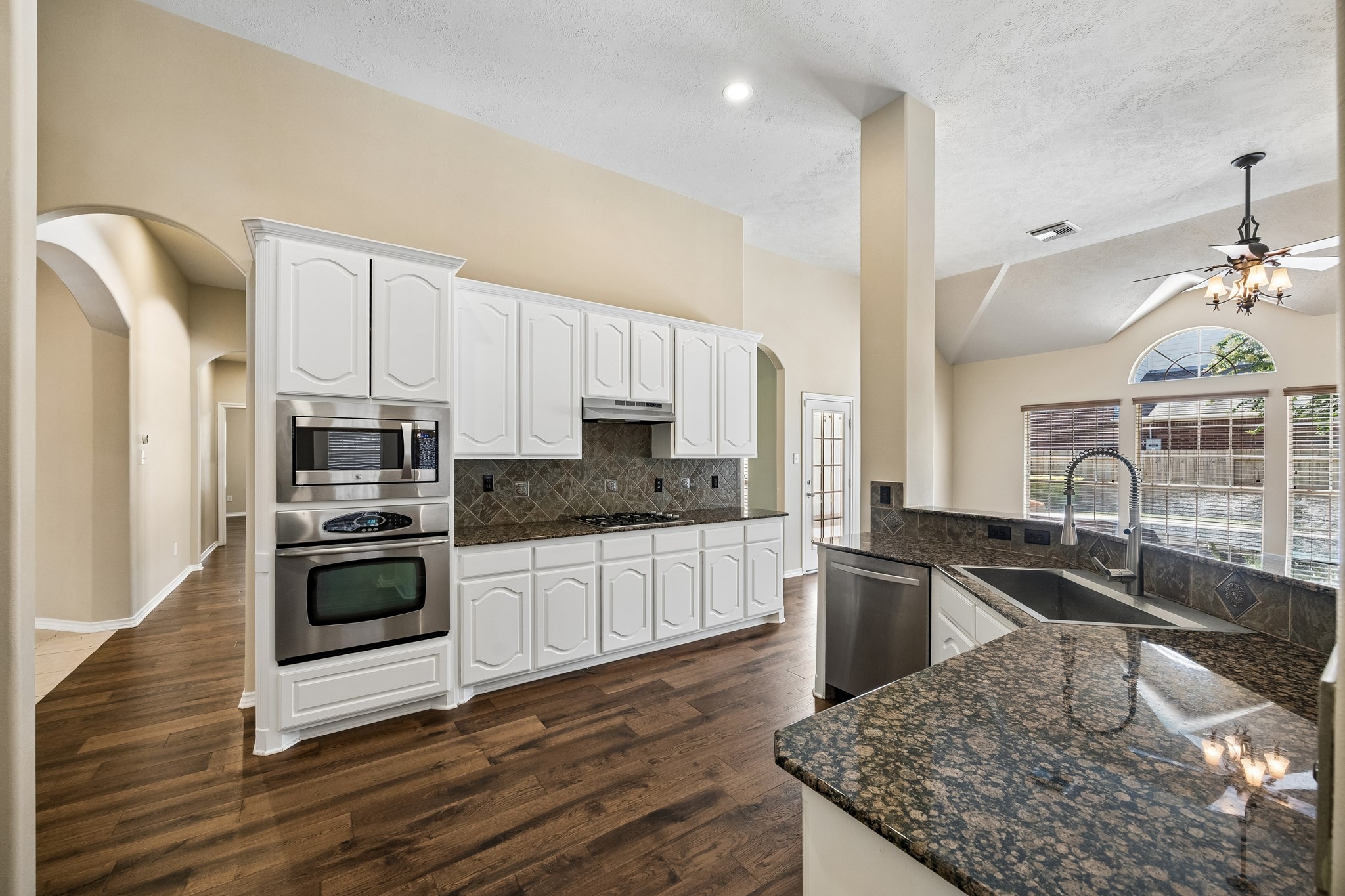 A second view of the spacious kitchen highlights the generous counter space, stainless steel appliances, crisp white cabinetry, and open sightlines to the family room, making it easy to stay connected while cooking and entertaining.