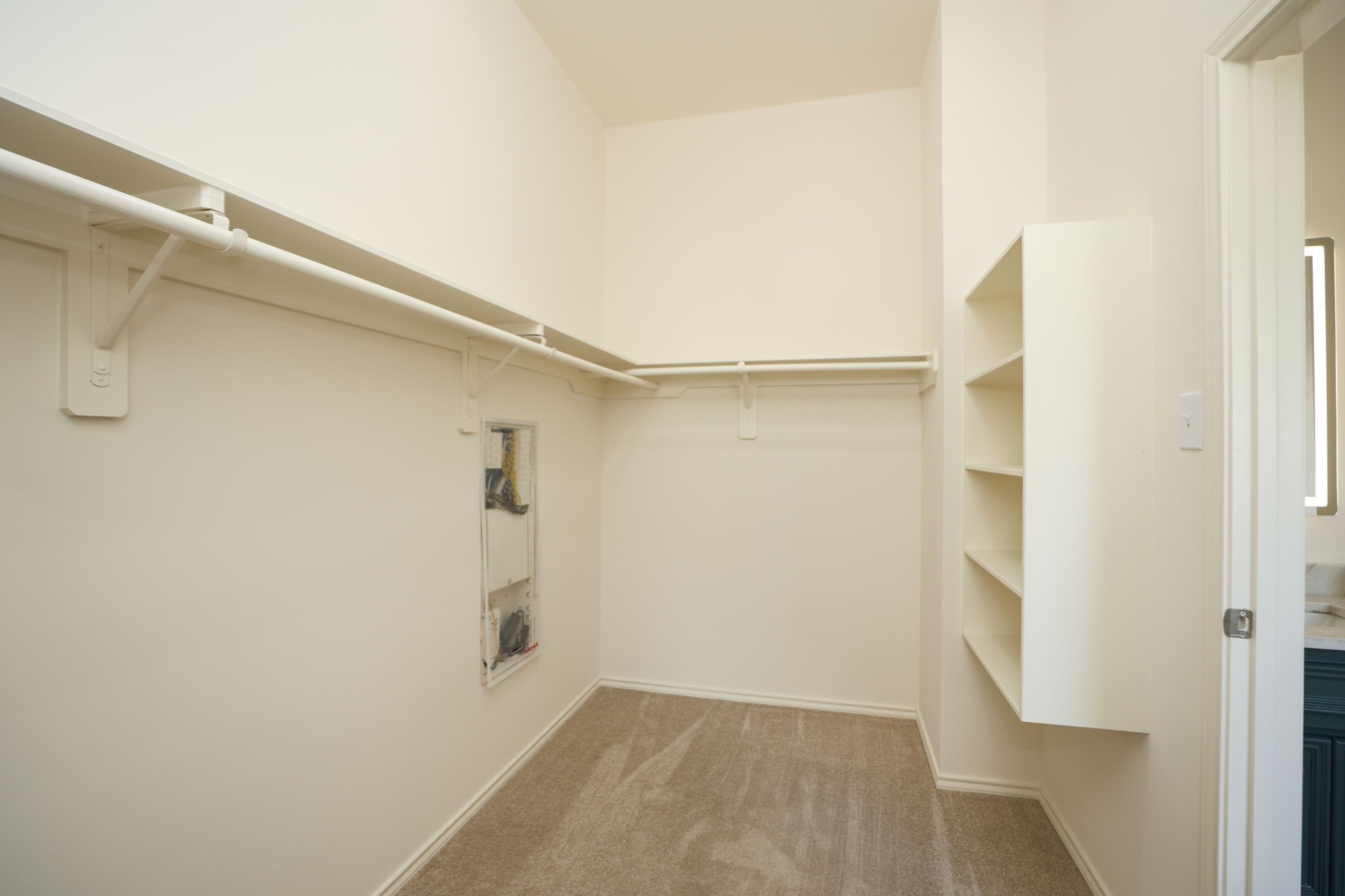 Generous walk-in closet with more storage behind the photographer.