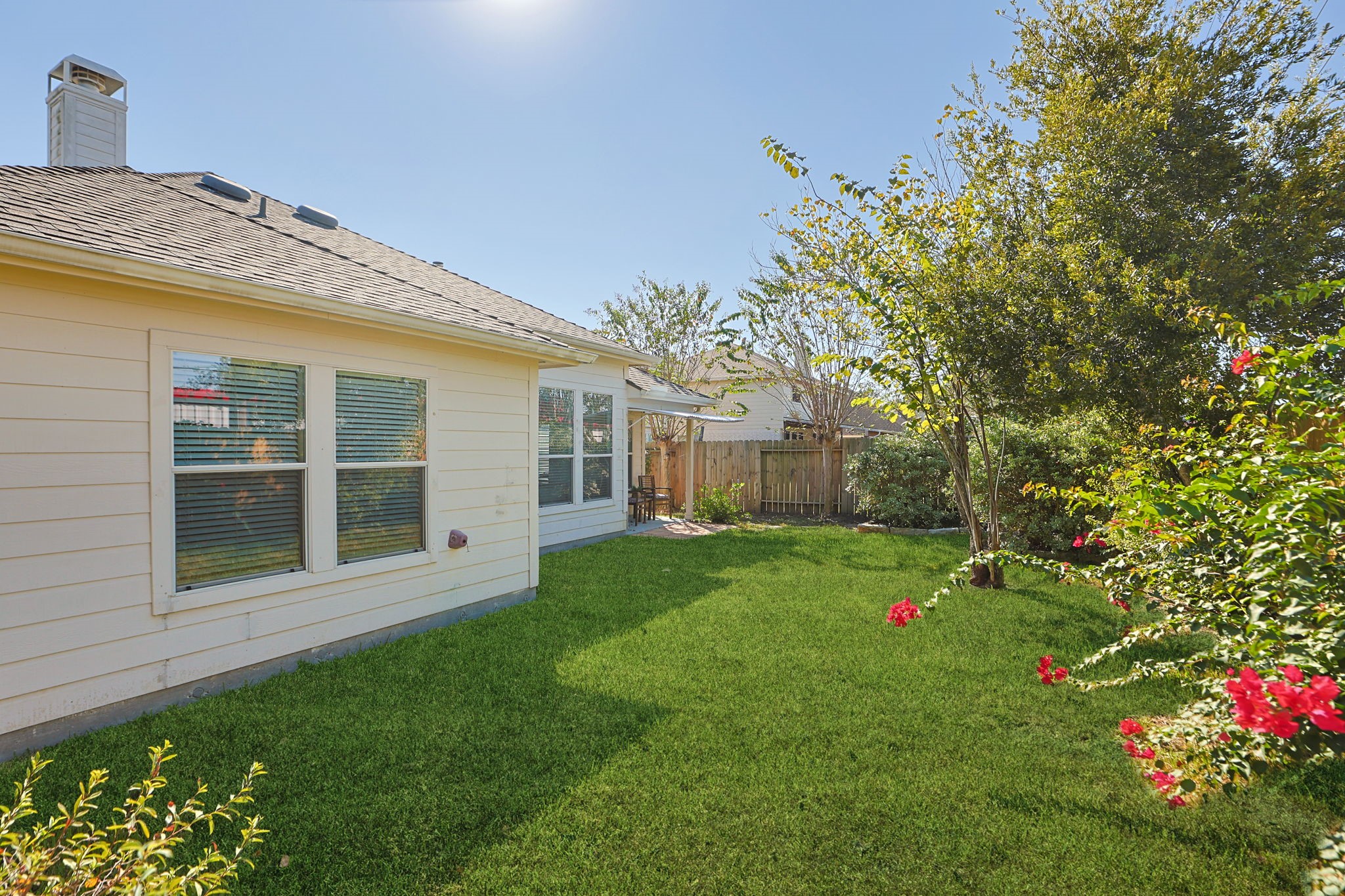 Lush landscaped back yard with grass, plants, and room to play.