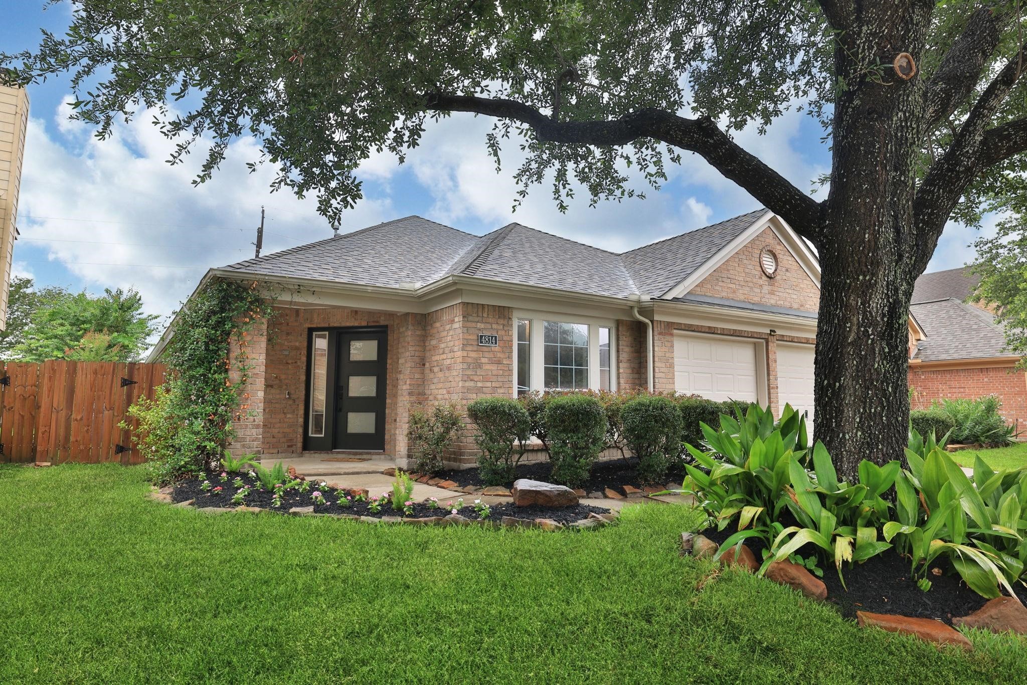 Fabulously landscaped yard with a neighborhood live oak out front.