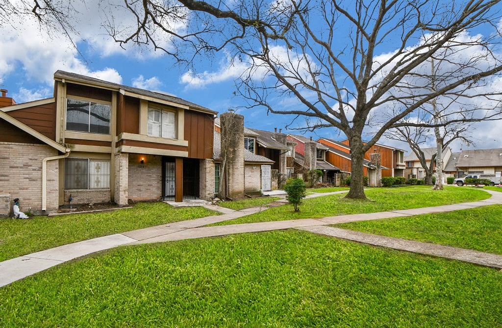 This photo showcases a row of two-story townhouses featuring mixed brick and wood exteriors. The homes are set along a curved, tree-lined path with well-maintained lawns, providing a welcoming neighborhood atmosphere.