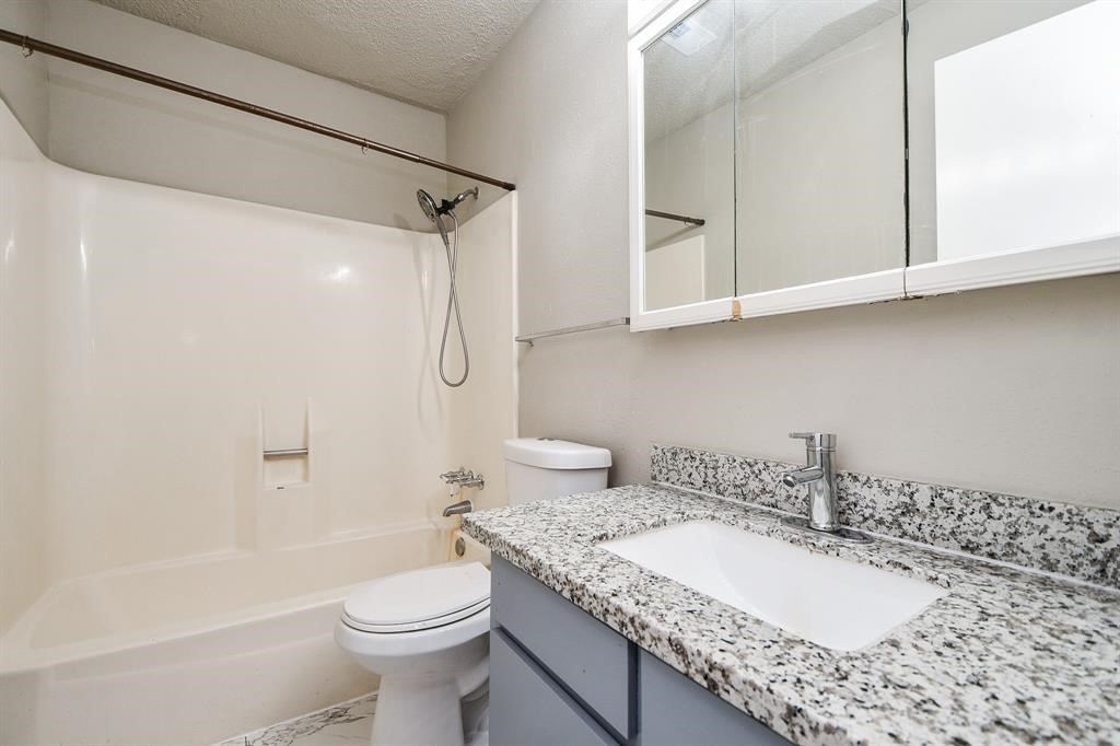 This bathroom features a clean, modern design with a granite countertop, an undermount sink, and a tub-shower combo. The neutral color palette and ample mirror space create a bright, functional space.