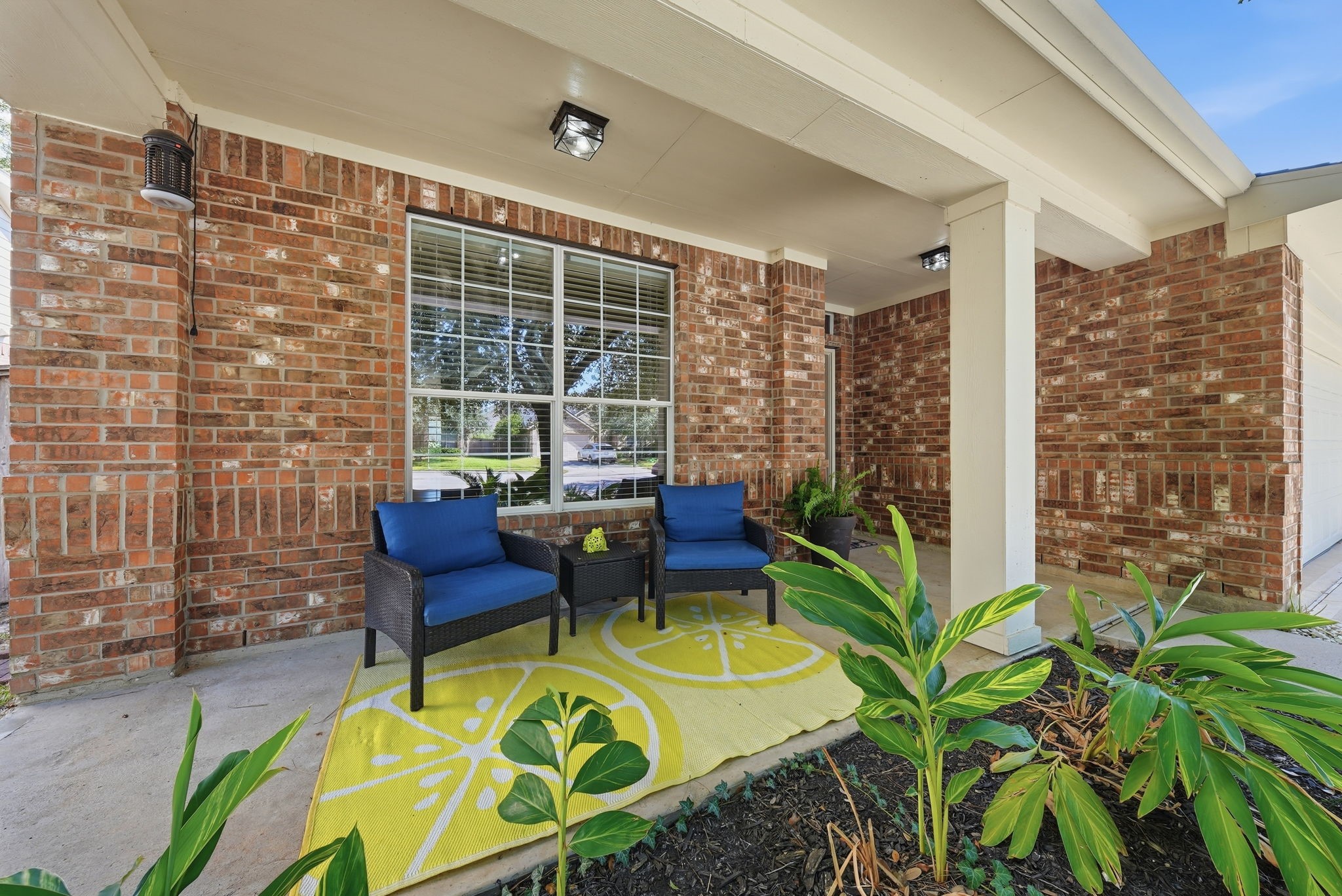 Covered front porch featuring new light fixtures and room for seatingthe perfect spot to enjoy morning coffee overlooking the landscaped front yard.